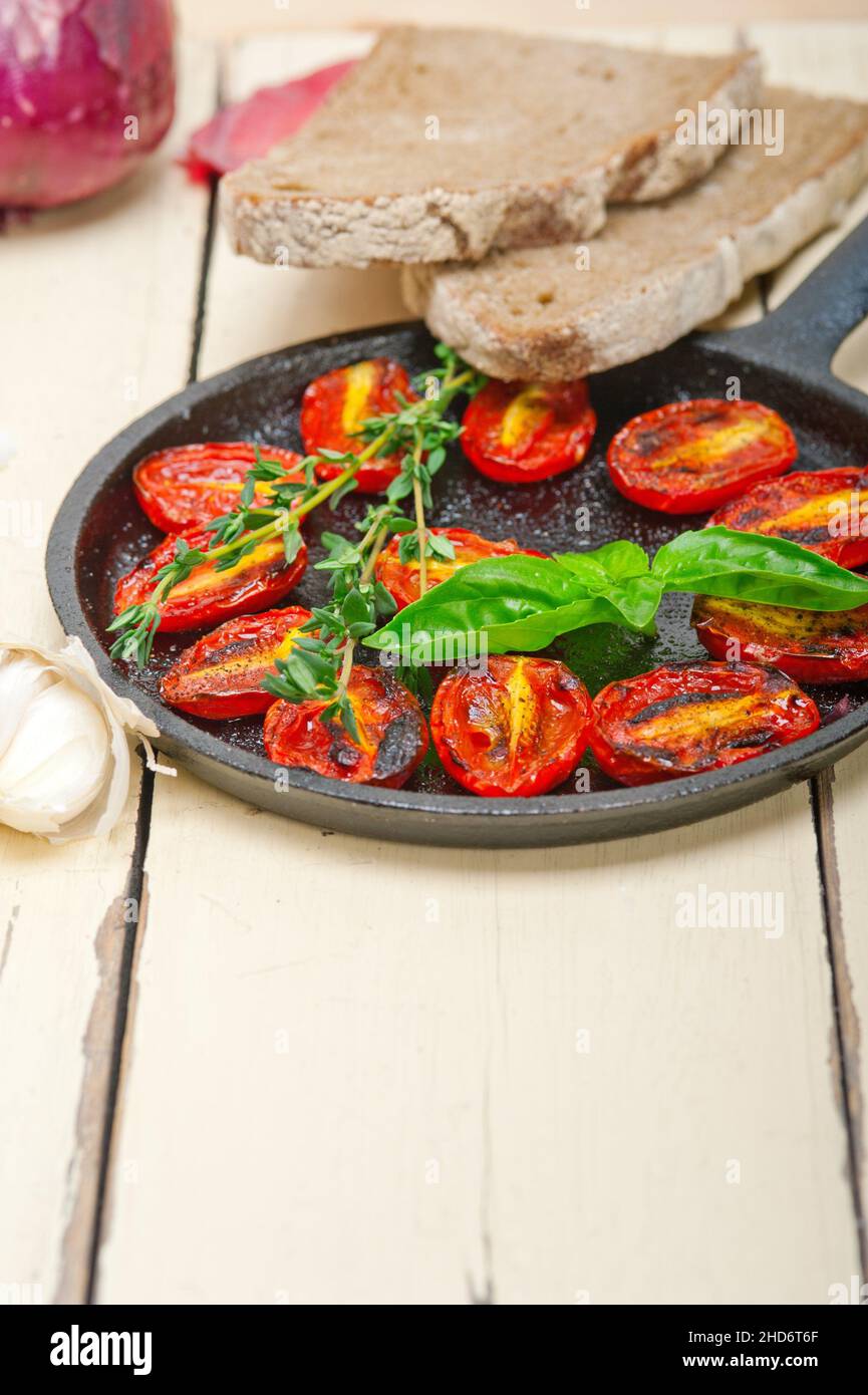 oven baked cherry tomatoes with basil and thyme on a cast iron skillet