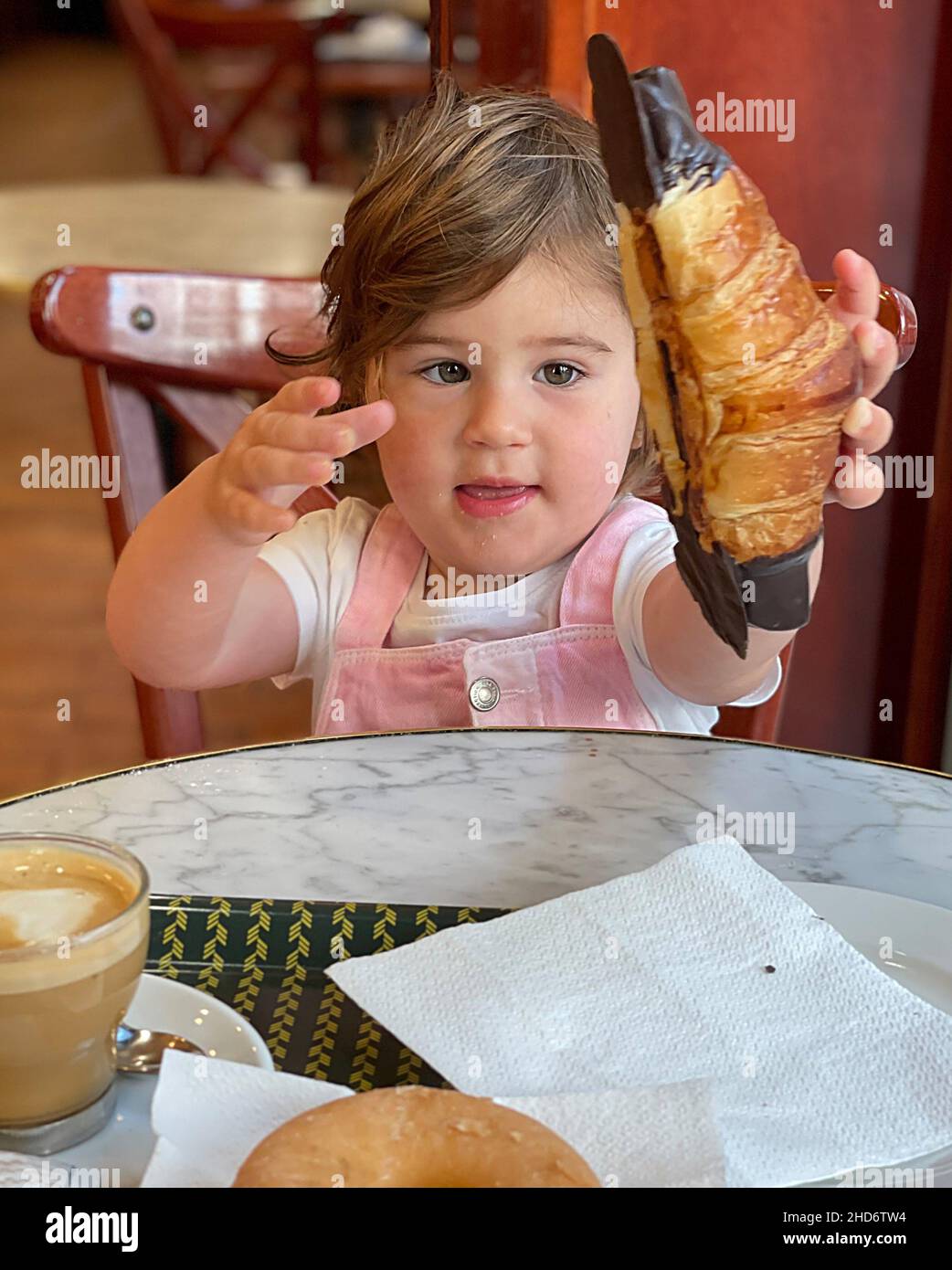 Girl picks up croissant with great appetite and eagerness. Stock Photo