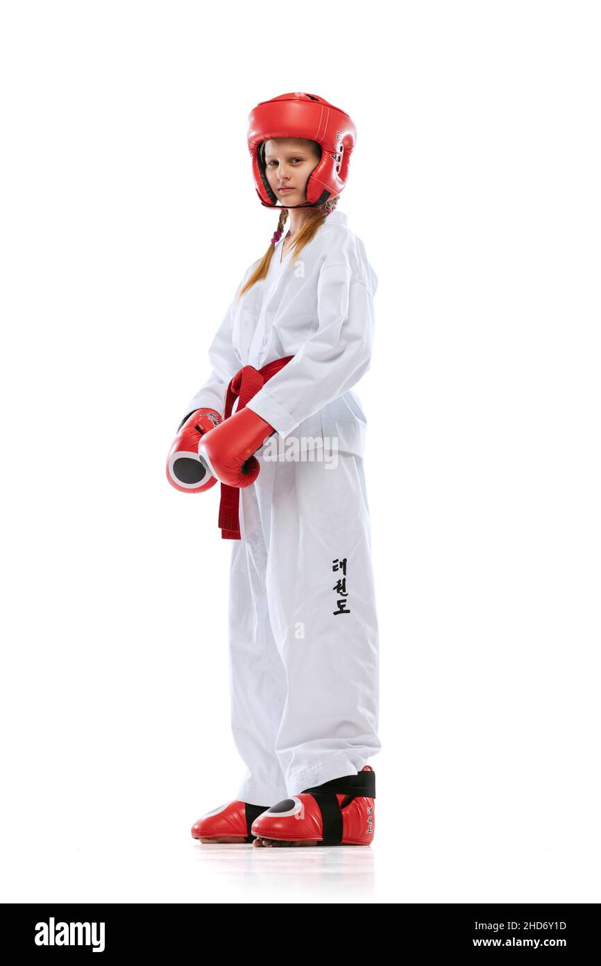 Full-length portrait of young girl, taekwondo athlete wearing dobok and sports defense uniform posing isolated on white background. Stock Photo