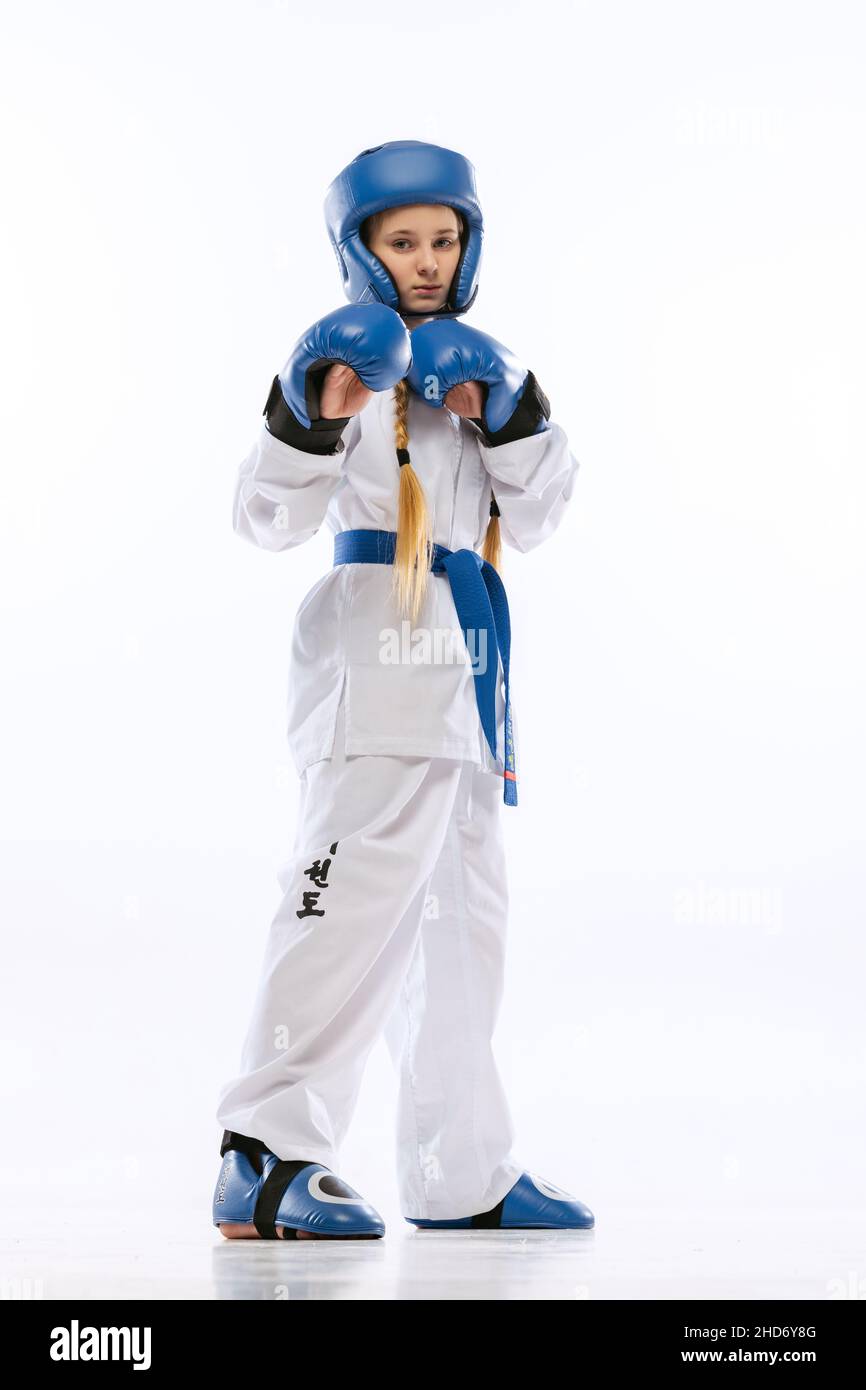 Full-length portrait of young girl, taekwondo athlete wearing dobok and sports defense uniform posing isolated on white background. Stock Photo