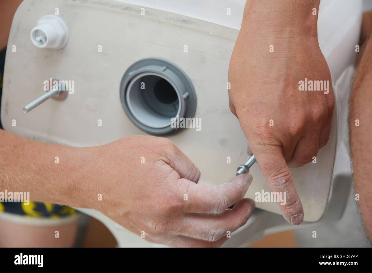 New toilet tank installation. A plumber is installing a toilet water