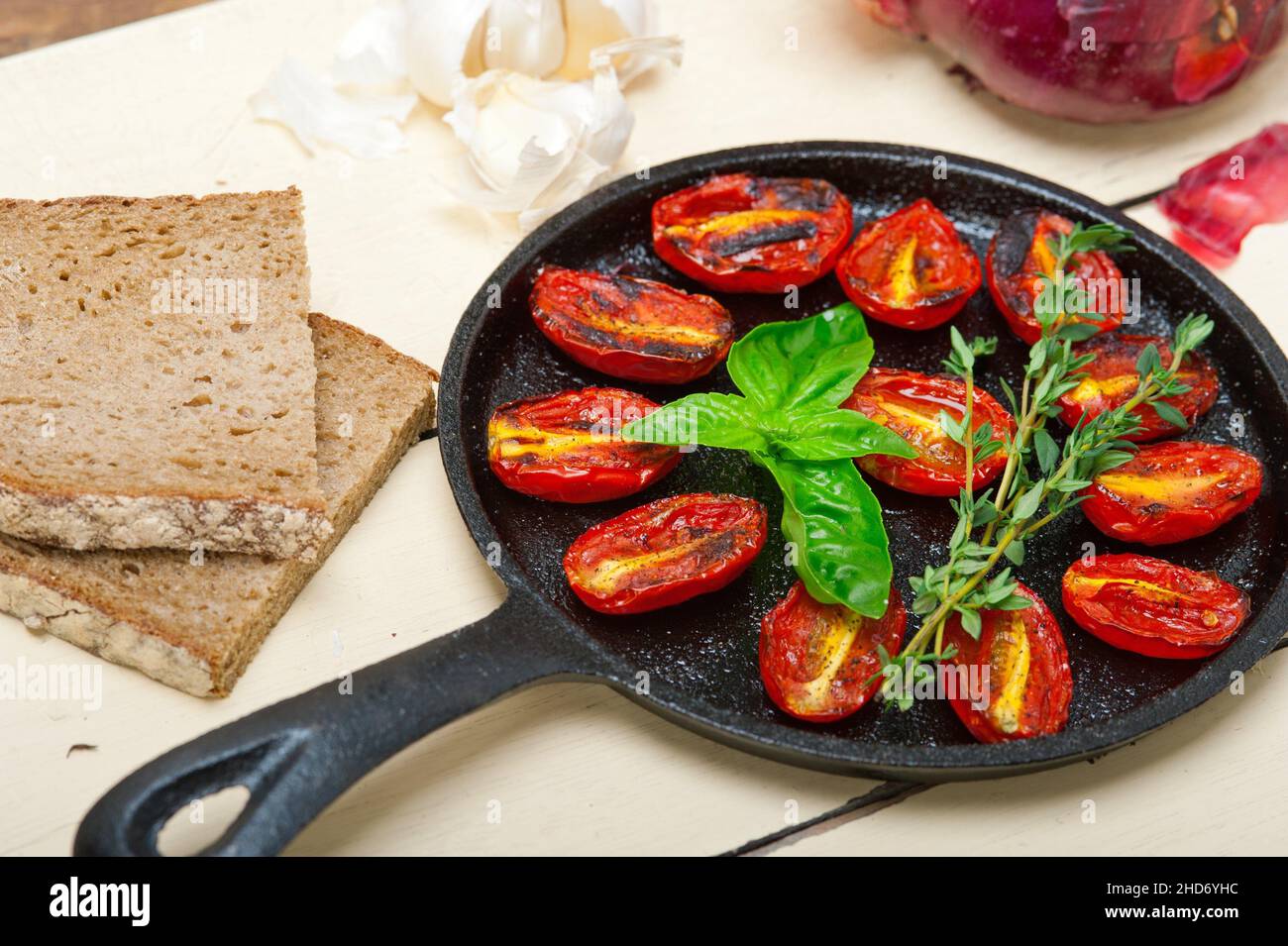 oven baked cherry tomatoes with basil and thyme on a cast iron skillet