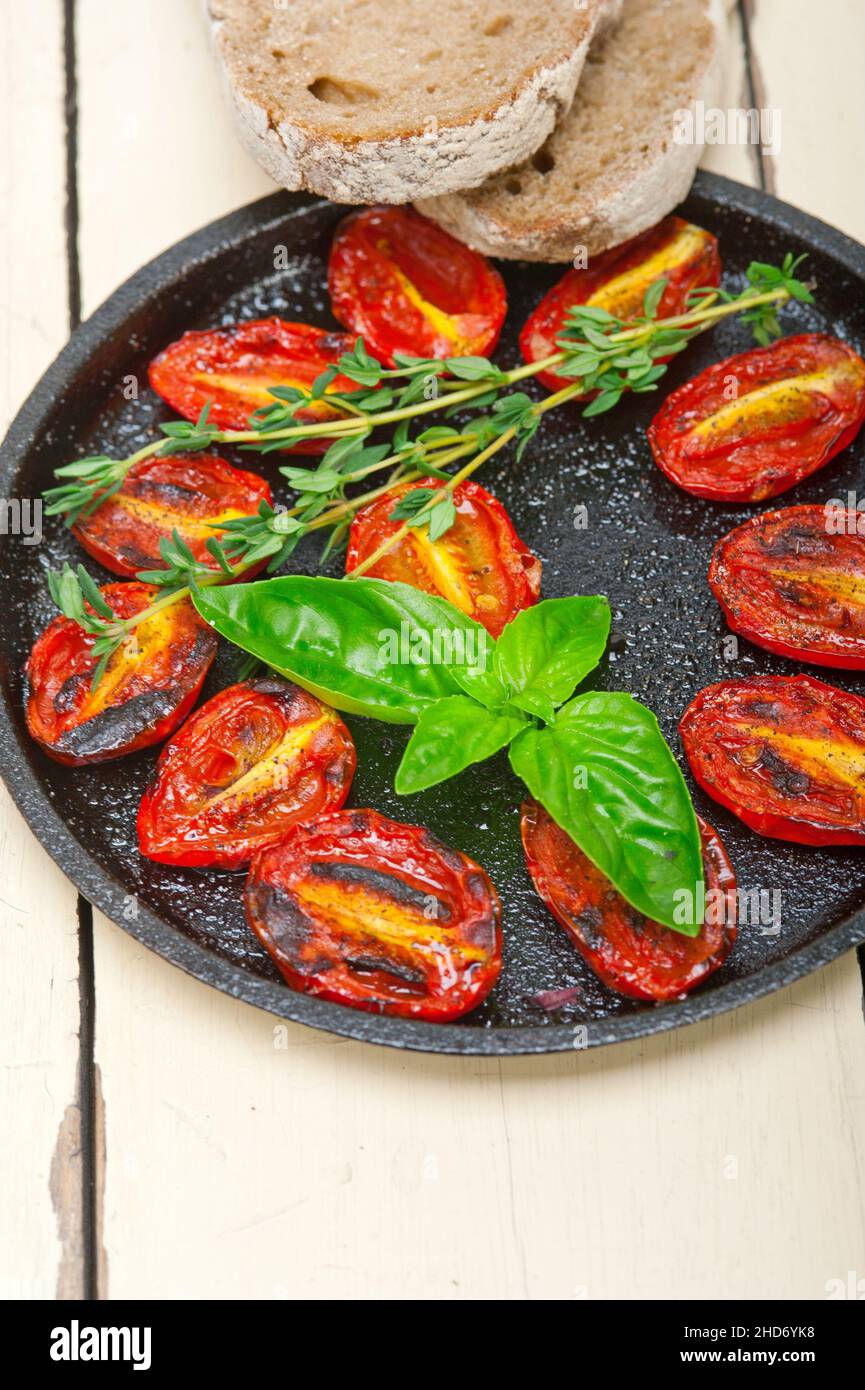 oven baked cherry tomatoes with basil and thyme on a cast iron skillet