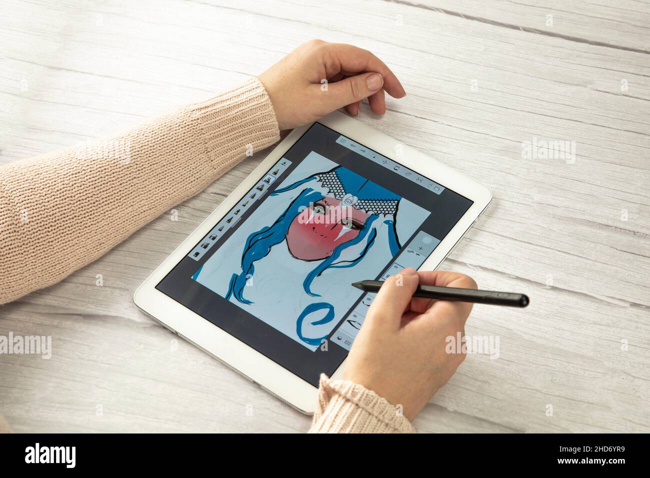 Young creative designer holding stylus pen drawing on screen of digital