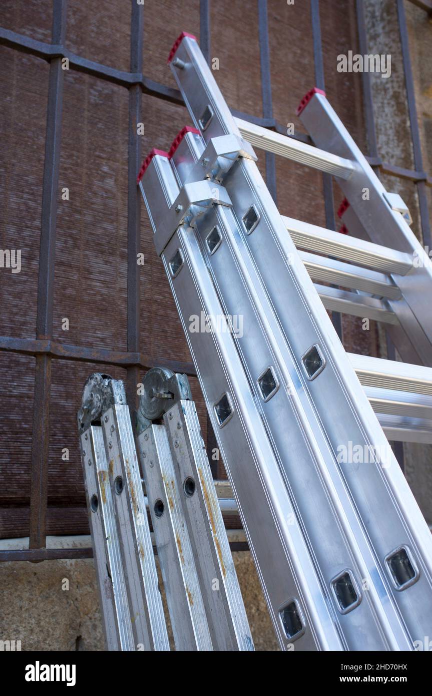 Professionals ladders folded stand over old town building. Extension and twin step multi-position ladders. Stock Photo