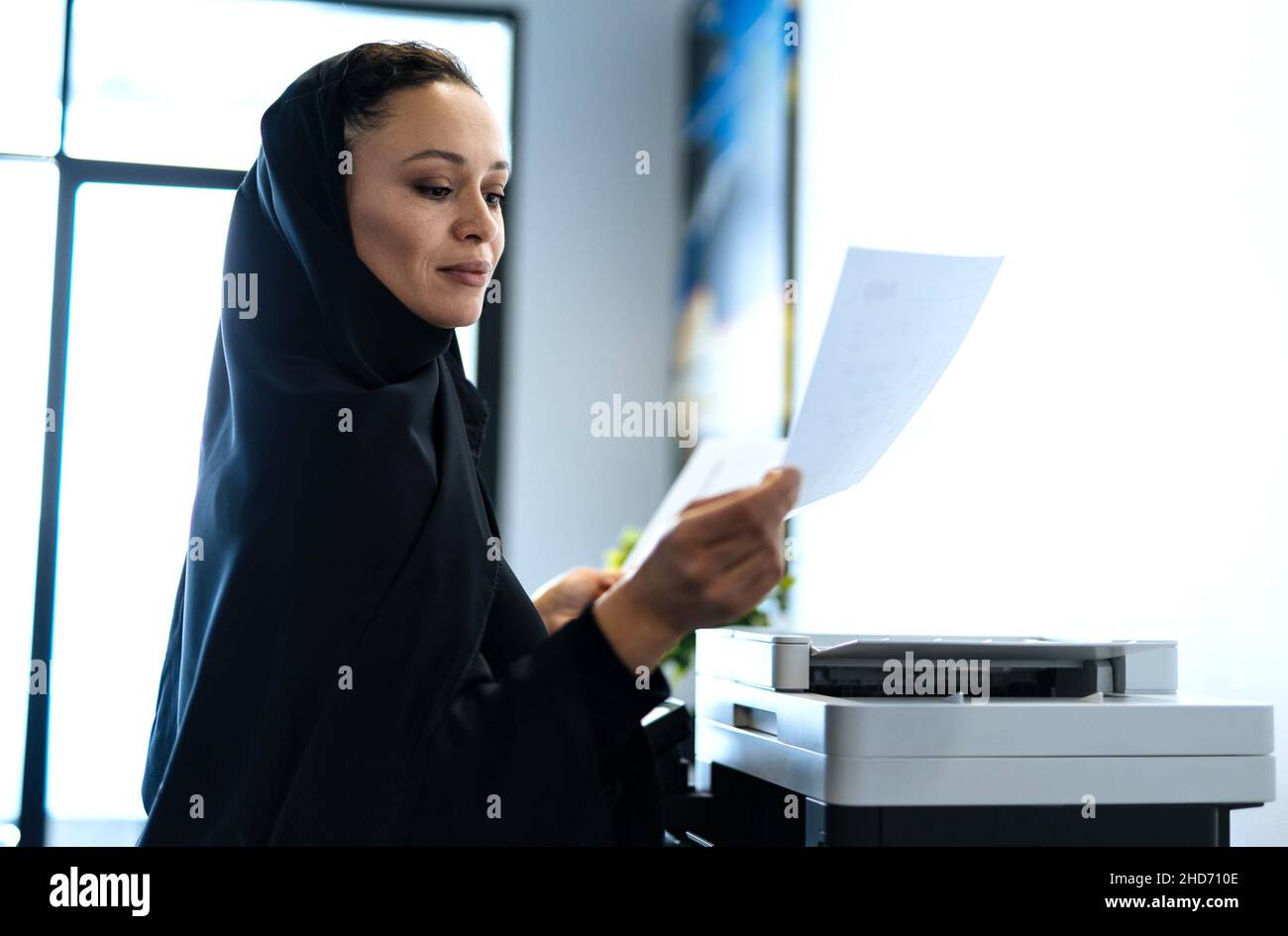 beautiful woman with abaya dress working and printing documents. Middle