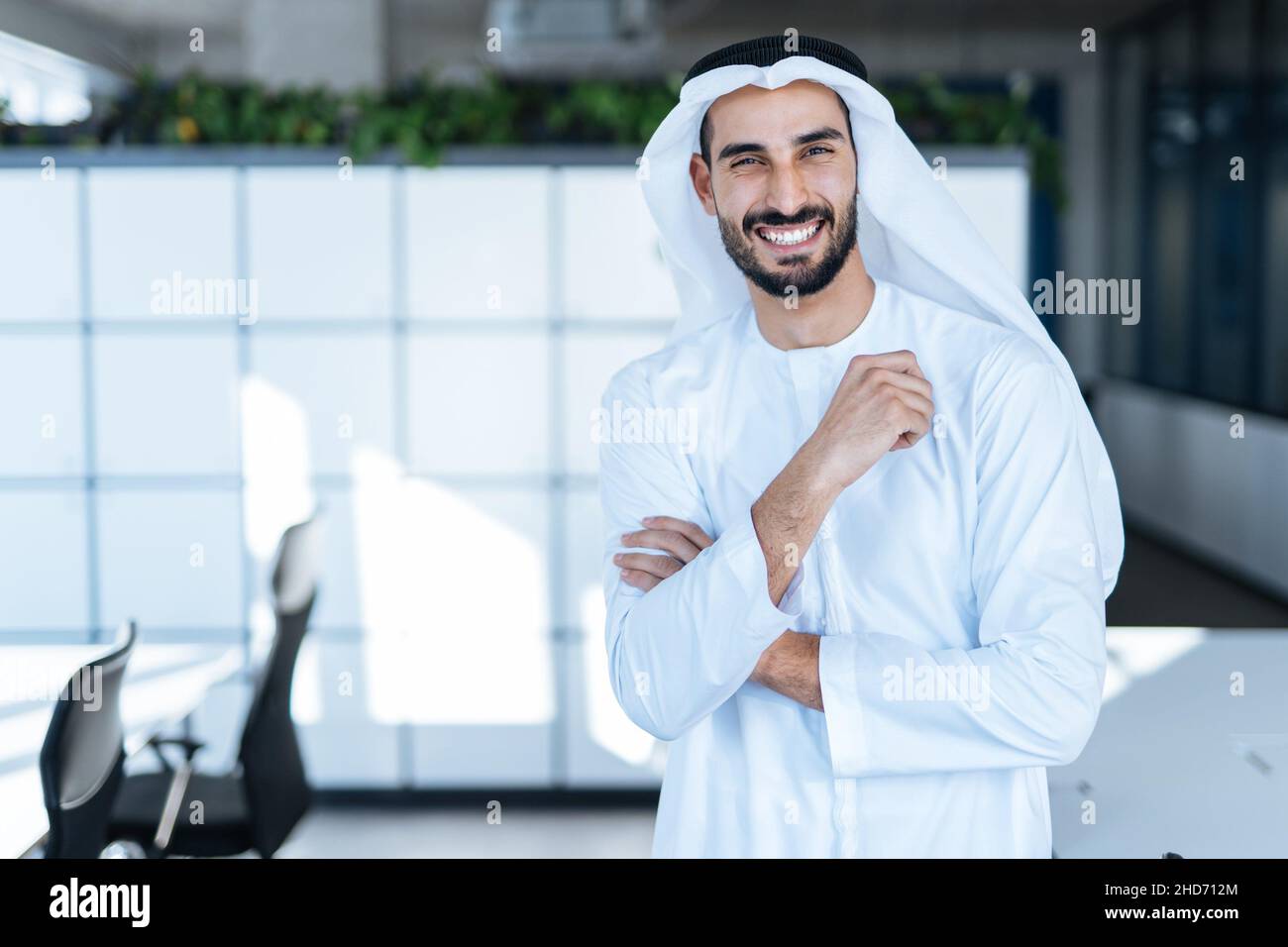 handsome man with dish dasha working in his business office of Dubai. Portraits of a successful businessman in traditional emirates white dress. Stock Photo