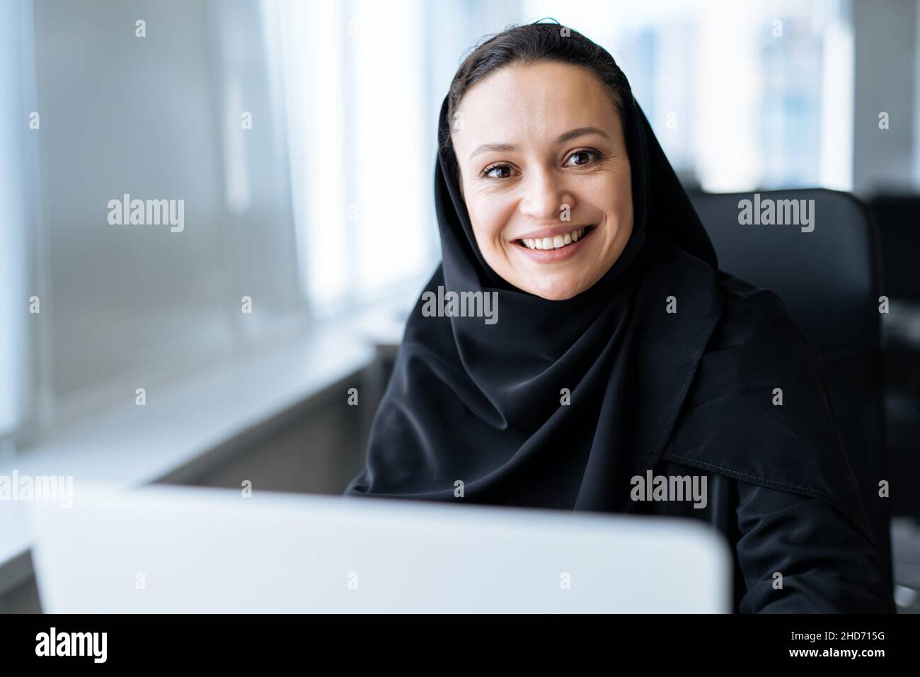 beautiful woman with abaya dress working on her computer. Middle aged