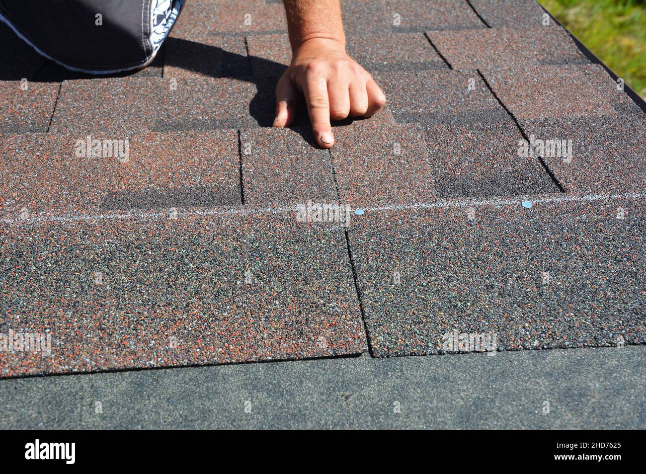 Asphalt roof shingles installation. A roofer is nailing bitumen