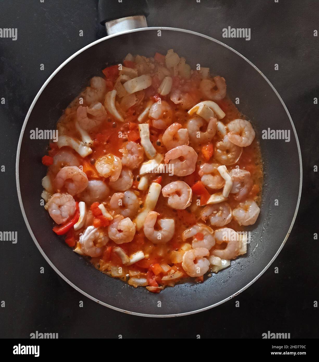 Fried Shrimps in Tomato Sauce (with onions, red peppers and squid rings). Stock Photo