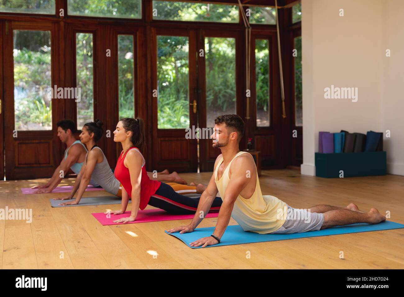Men and women practicing yoga pose during exercise class at health club Stock Photo
