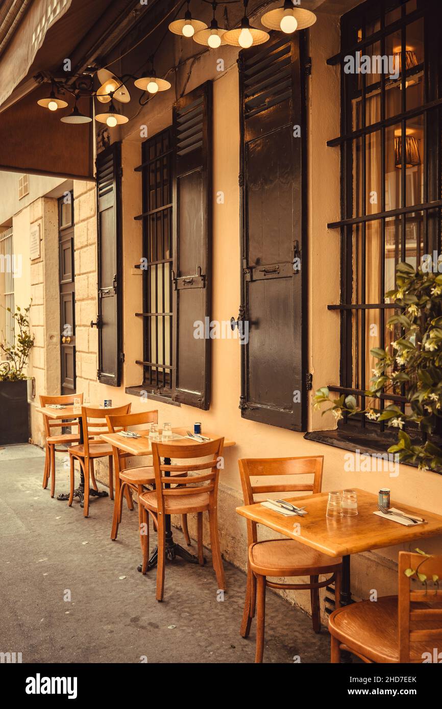 french restaurant - tables and chairs on the street in warm light - Paris, France Stock Photo