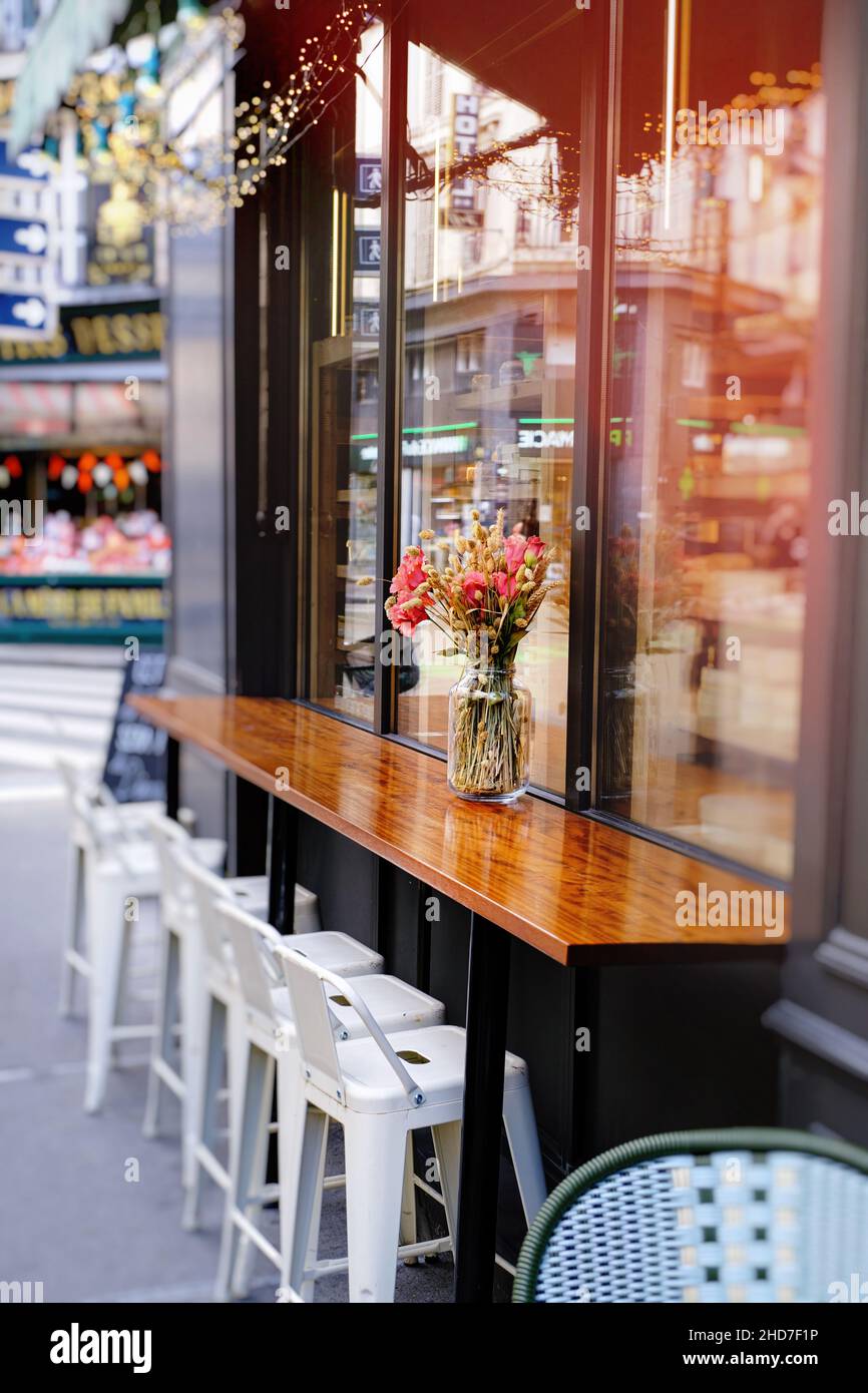 small french restaurant - chairs and table decorated with flowers on the street - Paris, France Stock Photo