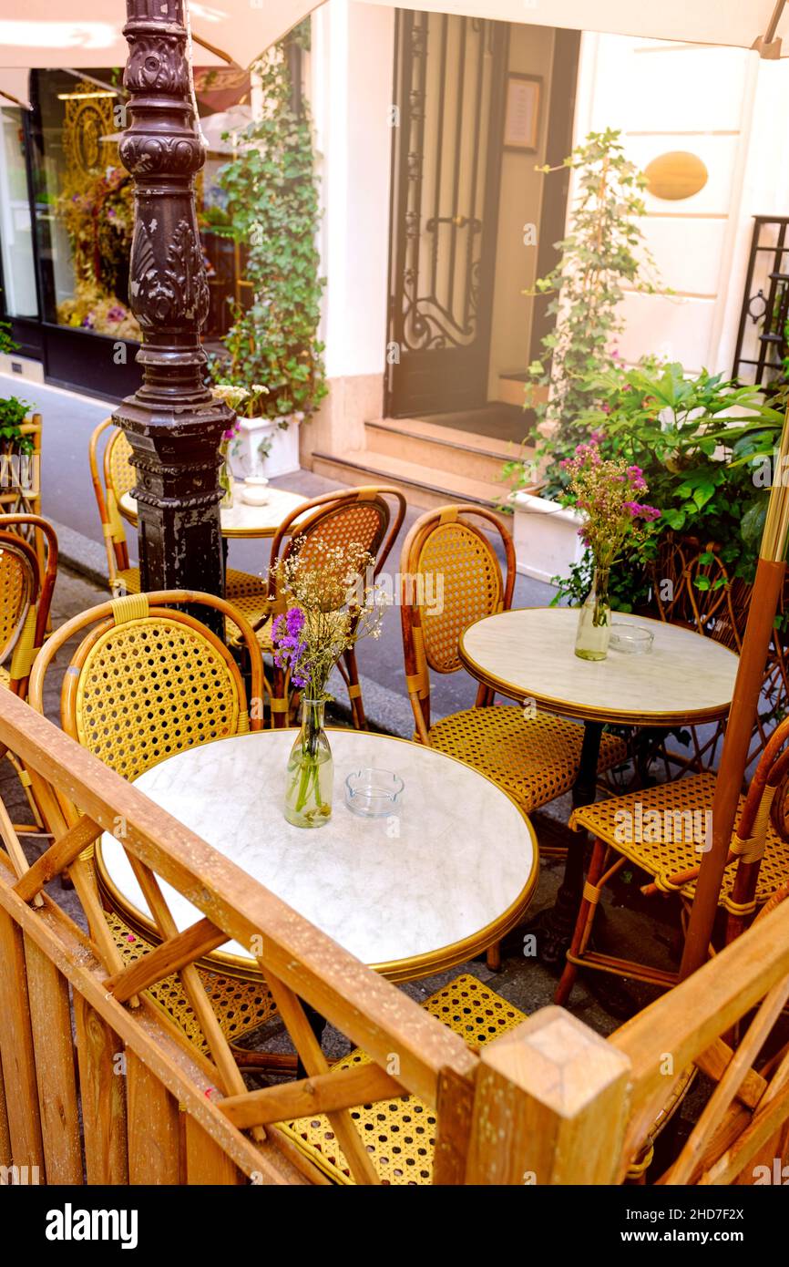 small french restaurant - table and chairs decorated with flowers on the street - Paris, France Stock Photo