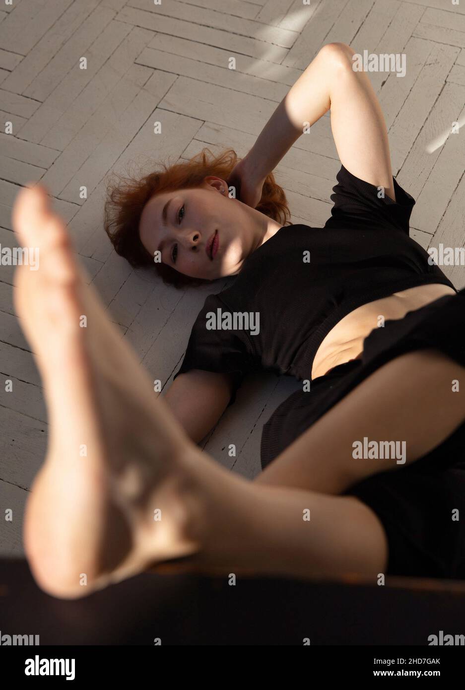 Young european woman with white skin on the floor in black clothes Stock Photo