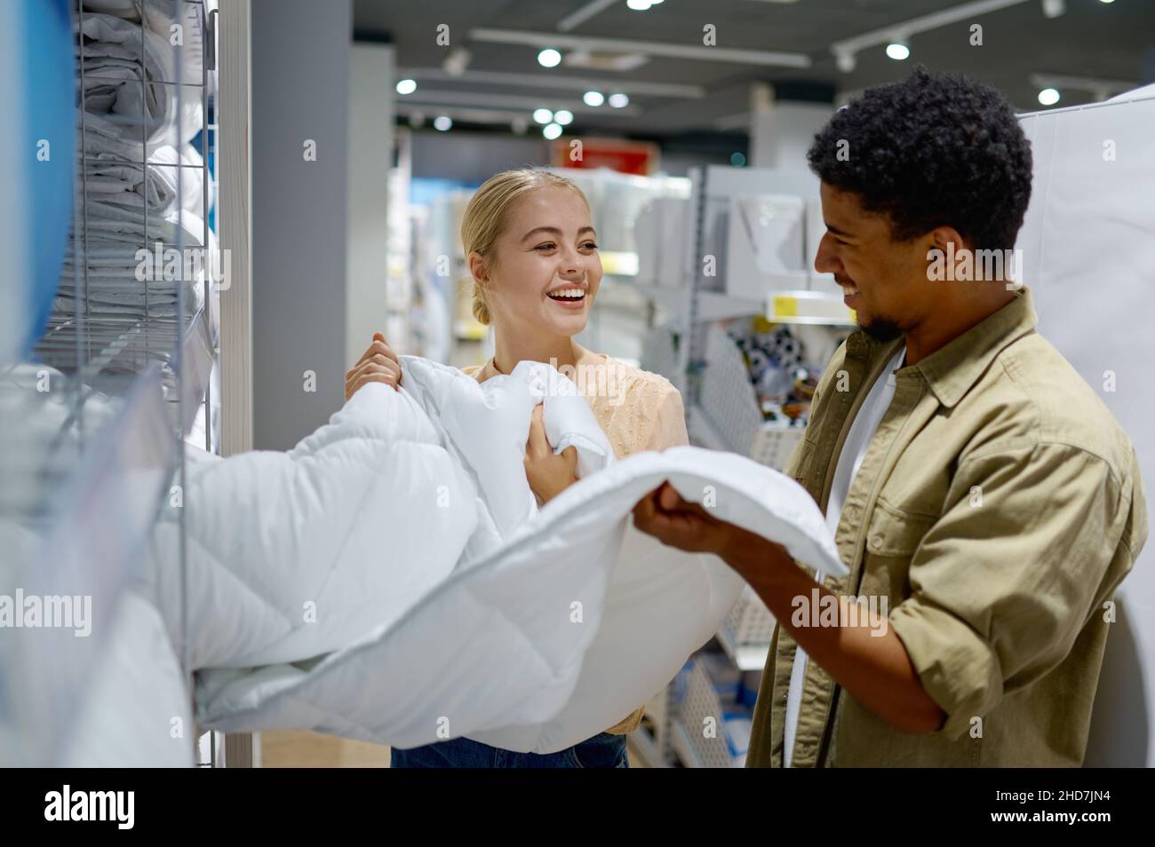 Happy multiracial couple buying blanket in store Stock Photo