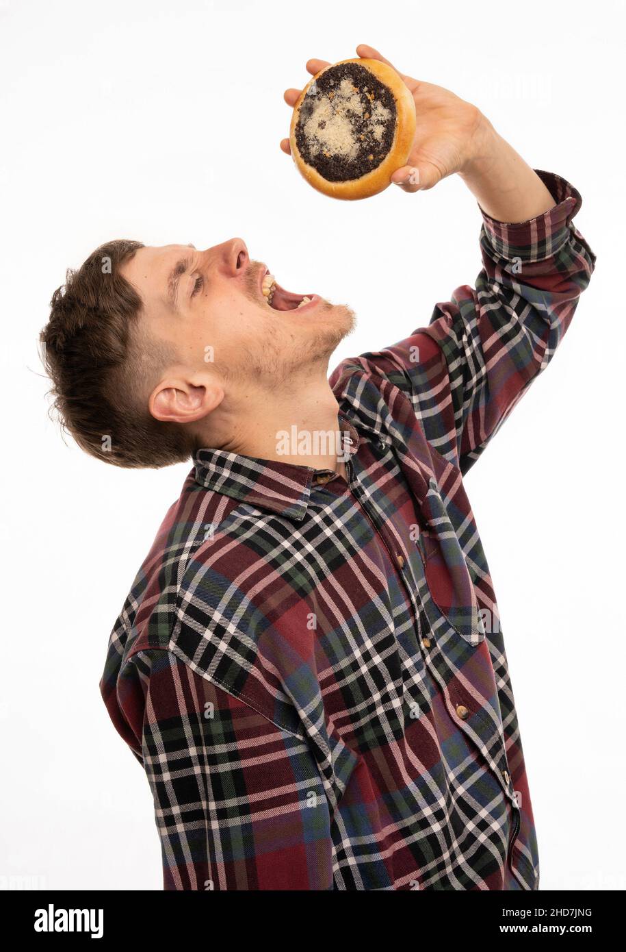 Young handsome tall slim white man with brown hair about to eat kolach in flannel shirt isolated on white background Stock Photo
