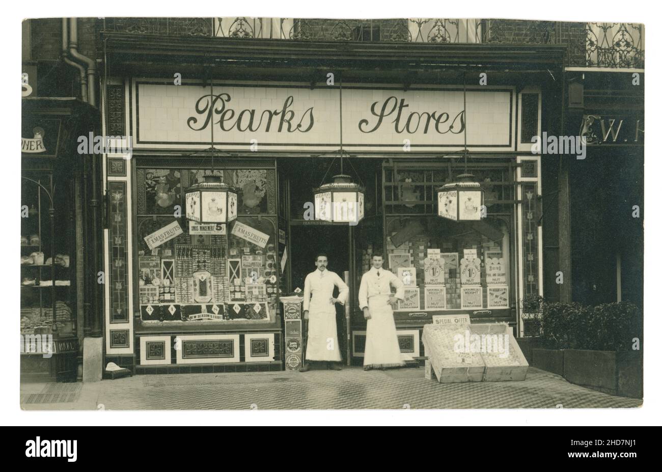 Original Edwardian postcard of Pearks Stores, grocery shop, shopfront, 2 shopkeepers stand outside. The store is selling Peark's butter, famous Huntley and Palmers biscuits, fresh eggs  Xmas fruit, homemade mincemeat at Christmas time, circa 1910, U.K. Stock Photo