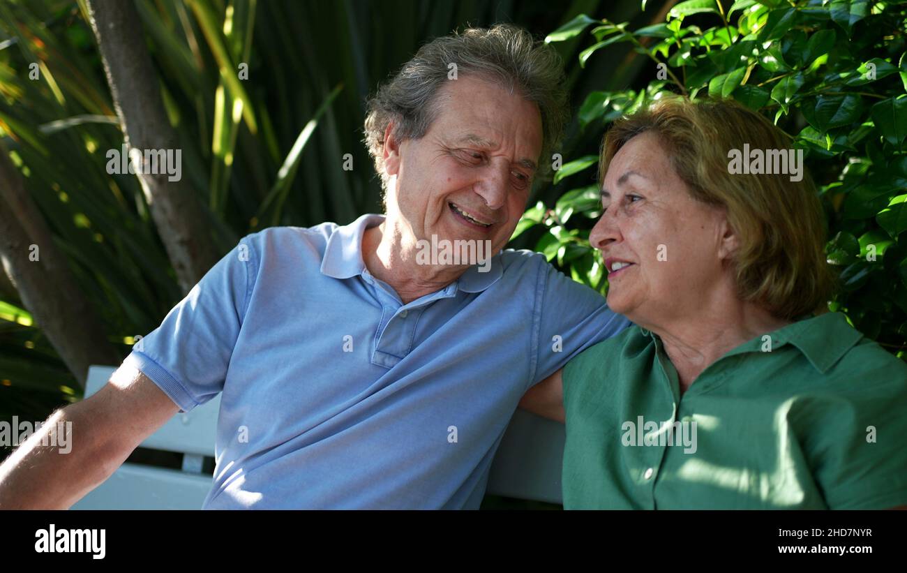 Happy senior couple sitting outside at park bench Stock Photo - Alamy