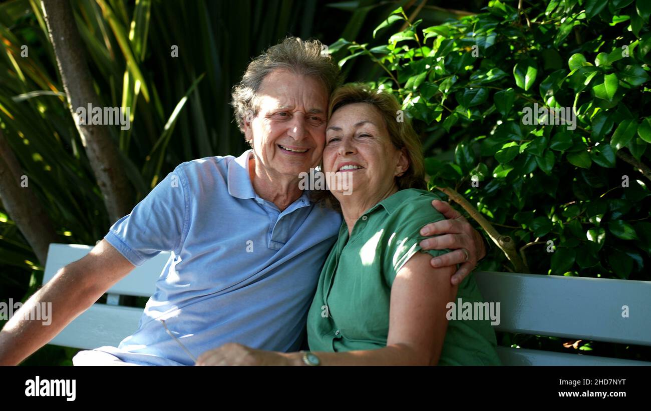 Happy senior couple sitting outside at park bench Stock Photo - Alamy