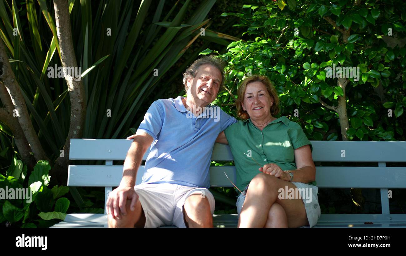 Happy senior couple sitting outside at park bench Stock Photo - Alamy