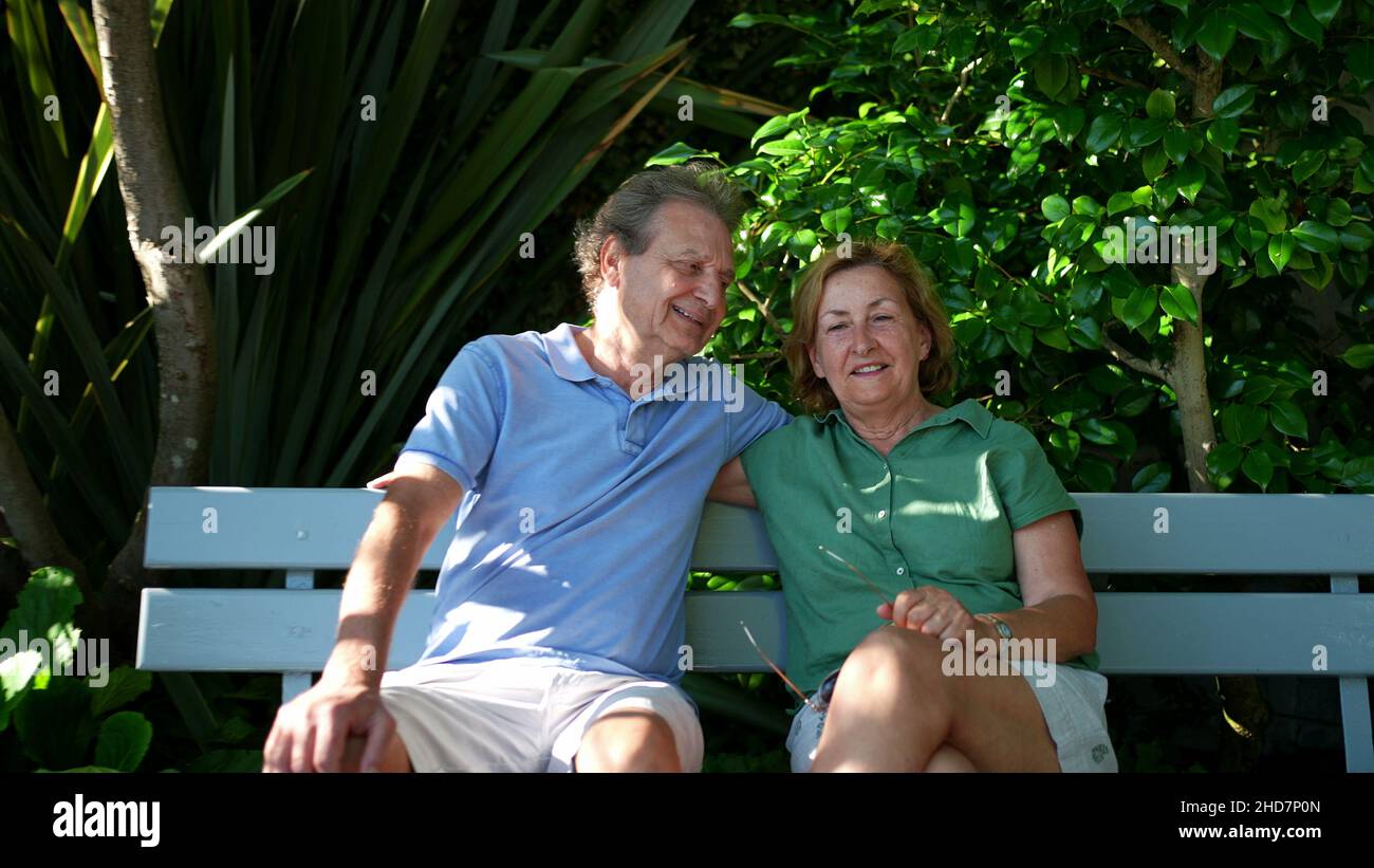 Happy senior couple sitting outside at park bench Stock Photo - Alamy