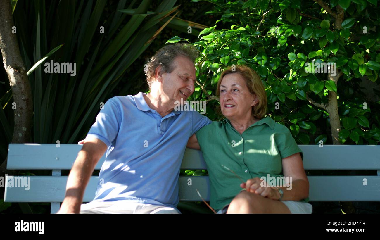 Happy senior couple sitting outside at park bench Stock Photo - Alamy