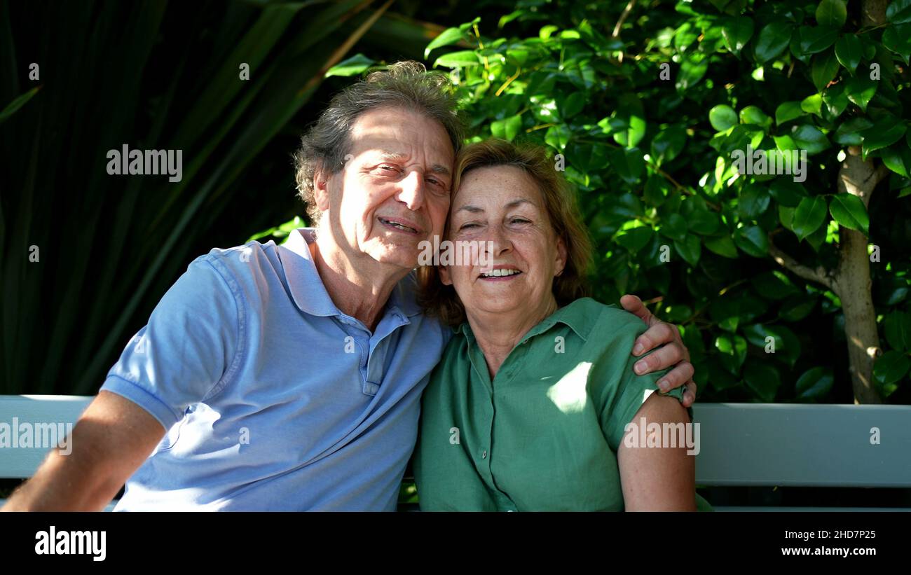 Happy senior couple sitting outside at park bench Stock Photo - Alamy