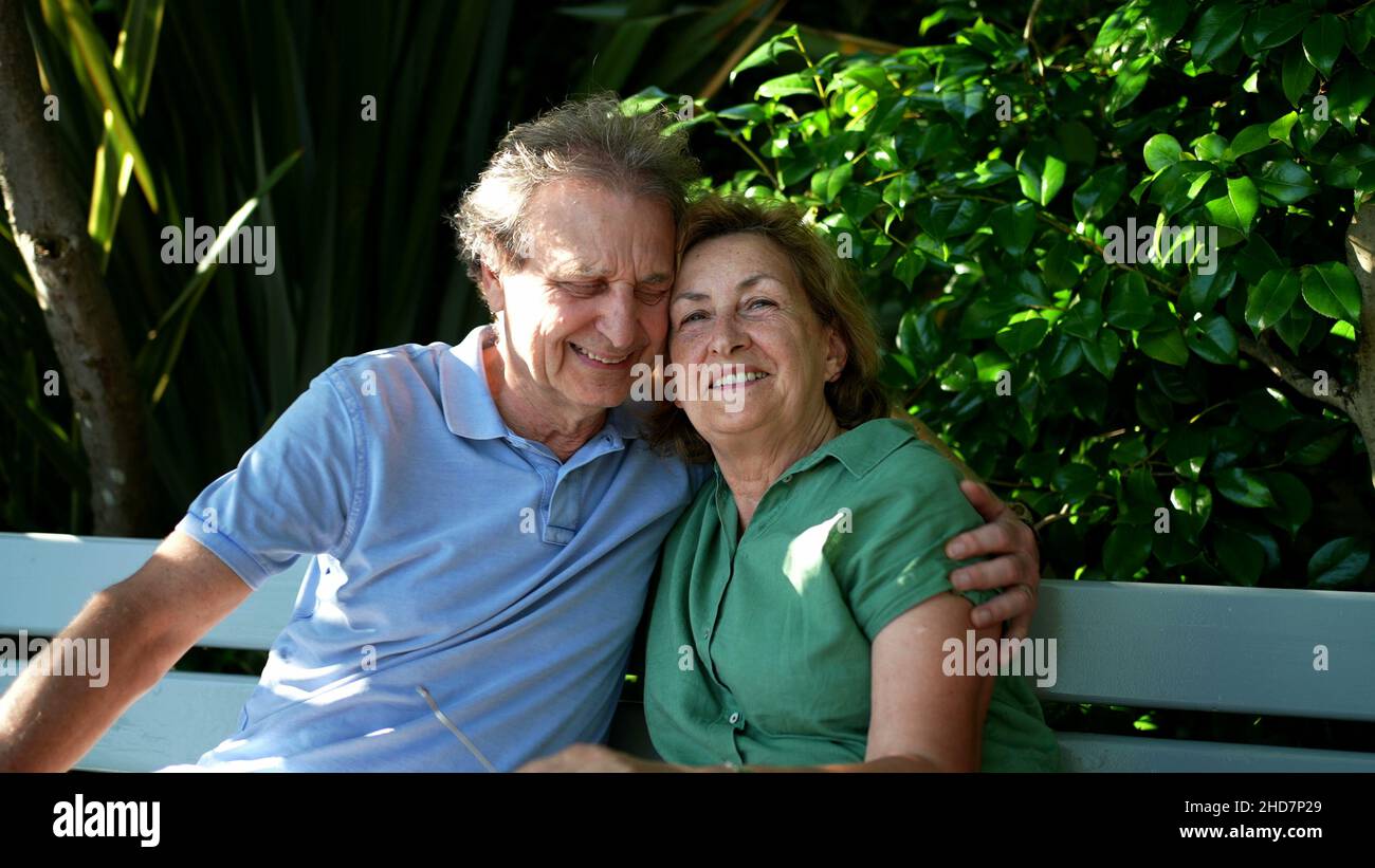 Happy senior couple sitting outside at park bench Stock Photo - Alamy