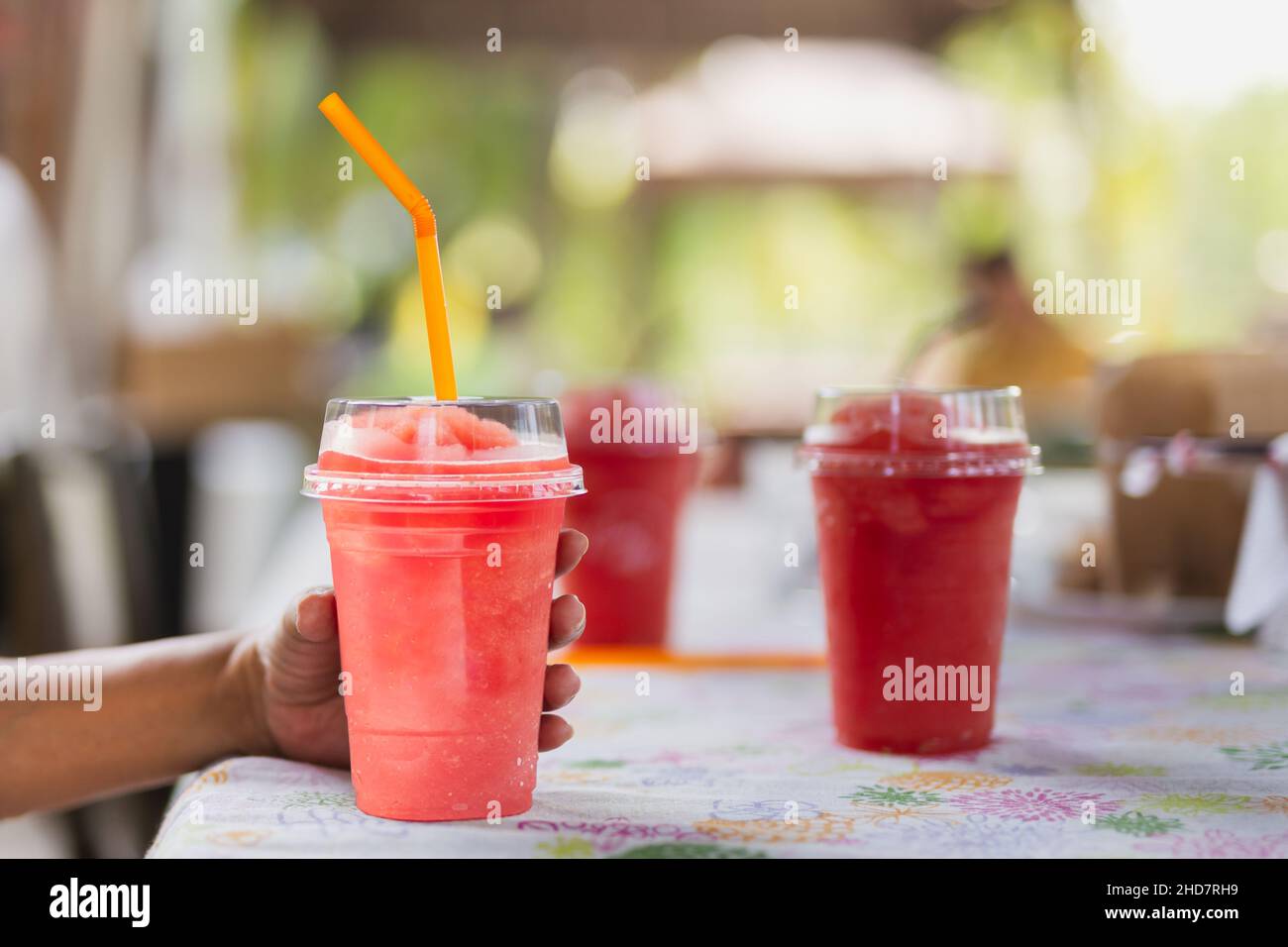 Female hand holding strawberry smoothie drink in plastic cup. Stock Photo