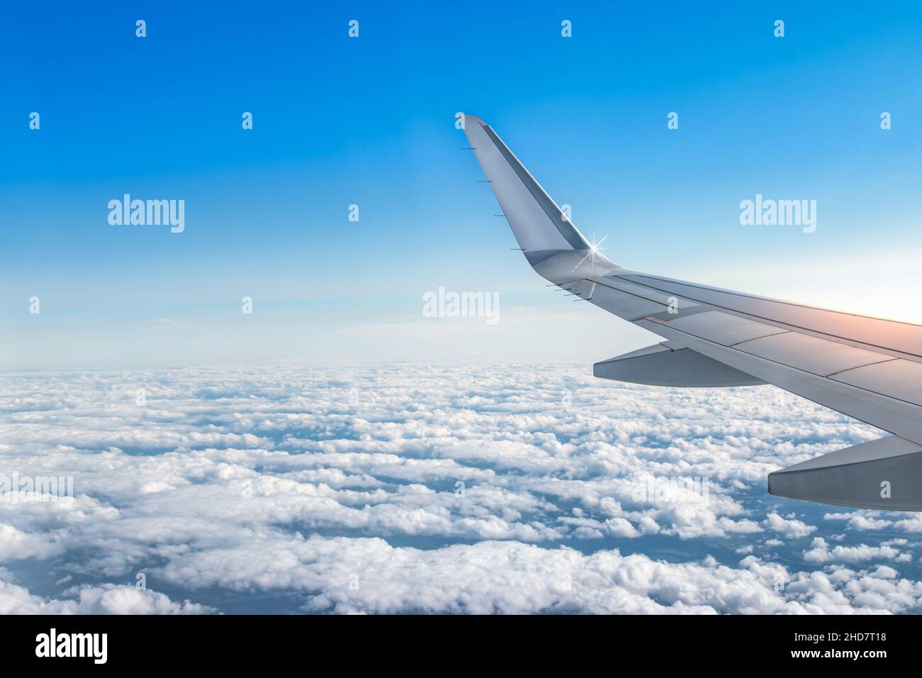 Airplane wing above the clouds at sunrise. Stock Photo