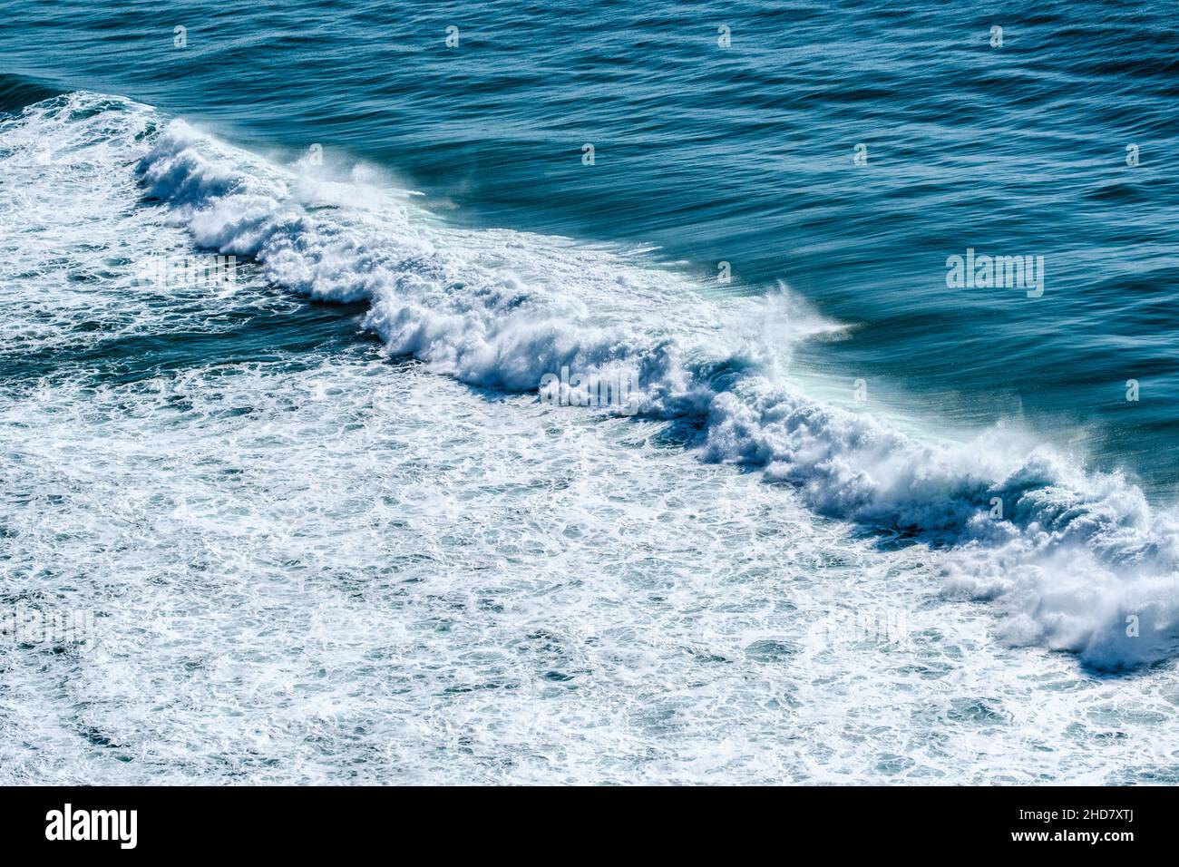 safire colored waves of the sea with its surf approaching the beach seen from above Stock Photo