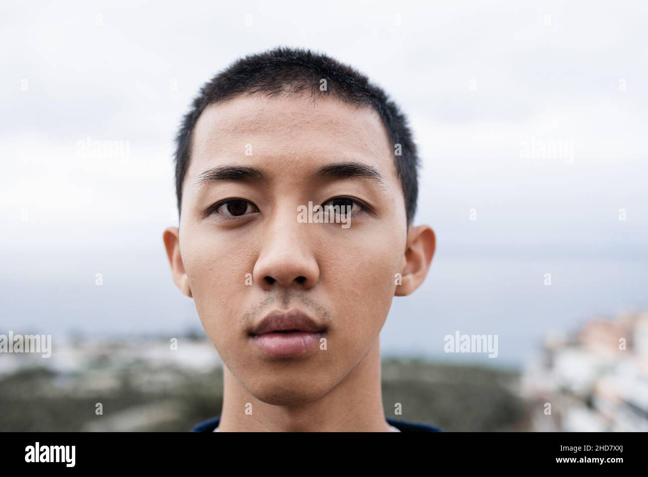 Young asian guy looking serious at camera outdoor - Focus on face