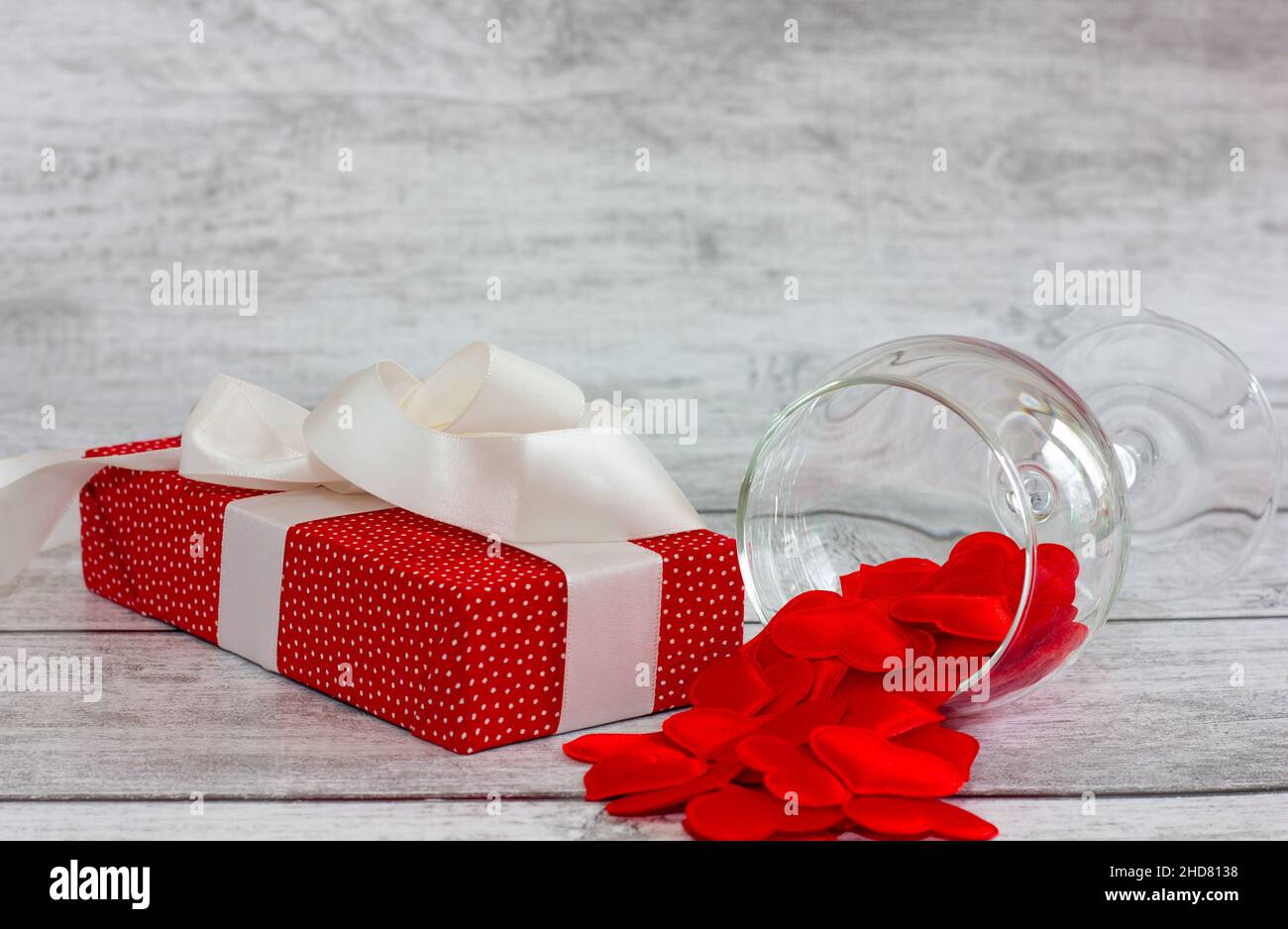 red gift box with pea pattern, white ribbon and heart on wooden background. holiday concept, valentine's day. Stock Photo