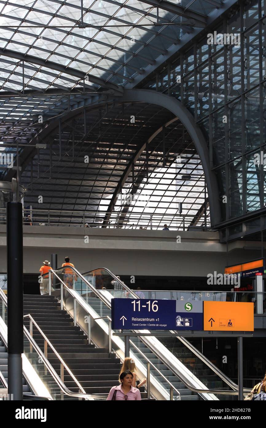 Interior of Berlin central train station with glass roof and people walking on stair and elevator in summer. Modern architecture design. Stock Photo