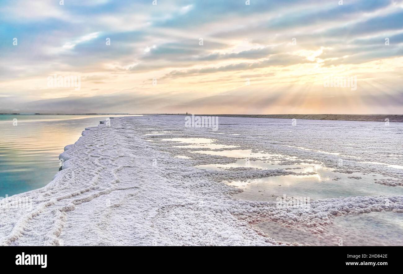 Morning sun shines on salt crystals formations, clear cyan green calm water near, typical landscape at Ein Bokek beach, Israel Stock Photo