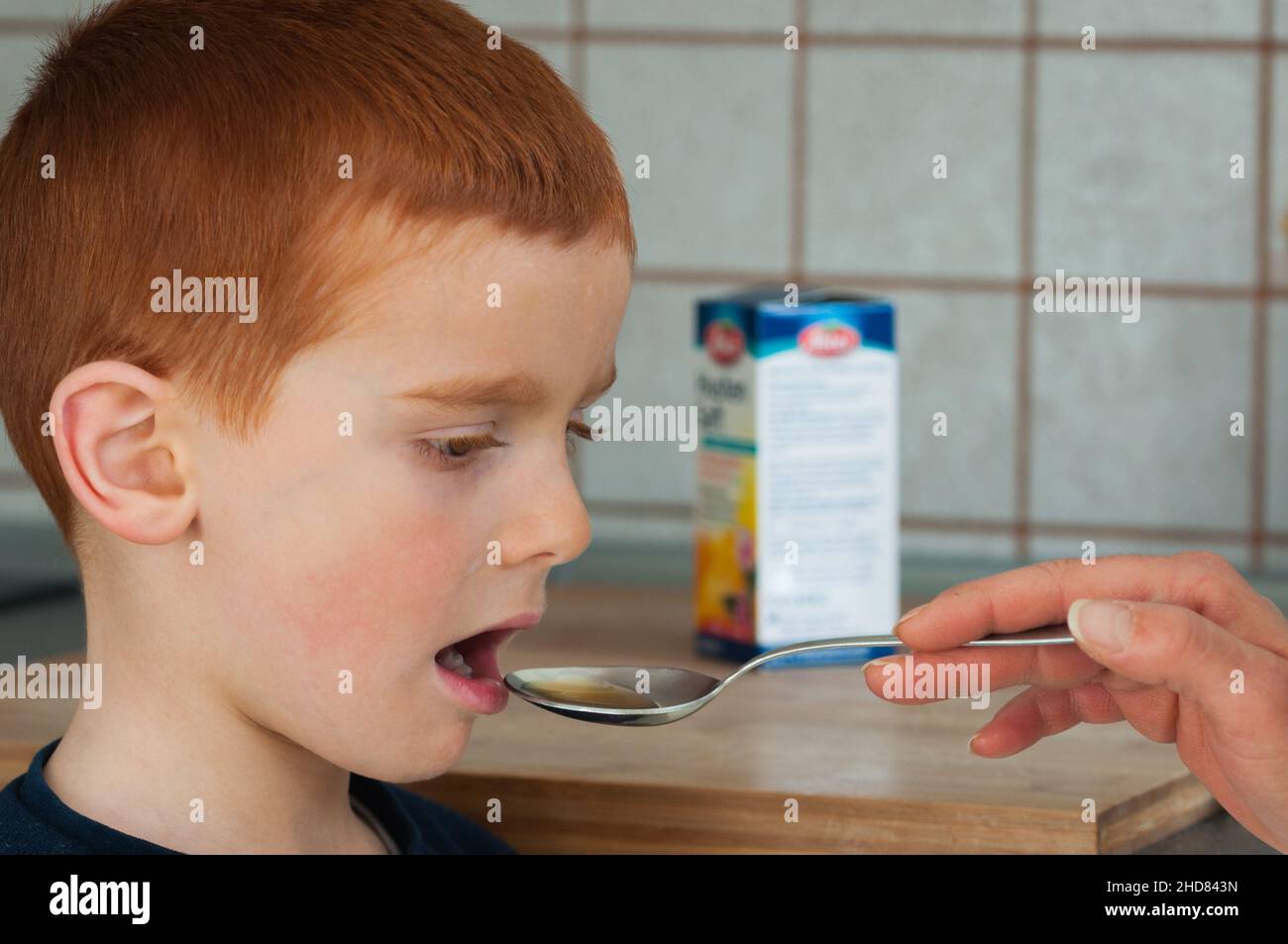 child takes a spoonful of cough syrup Stock Photo