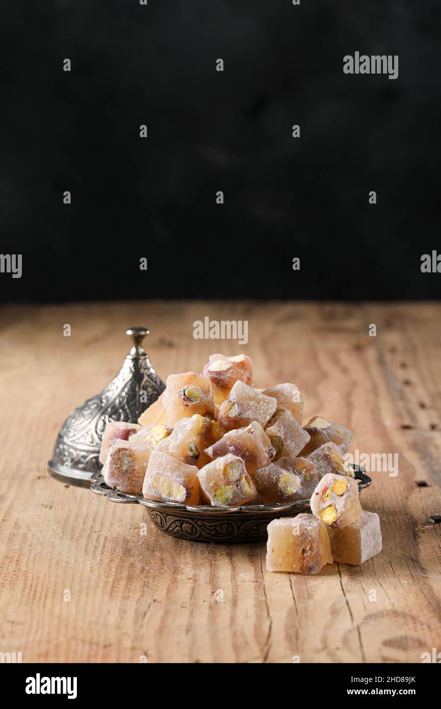 Turkish delight with pistachio in a copper plate on a wooden floor, text space Stock Photo