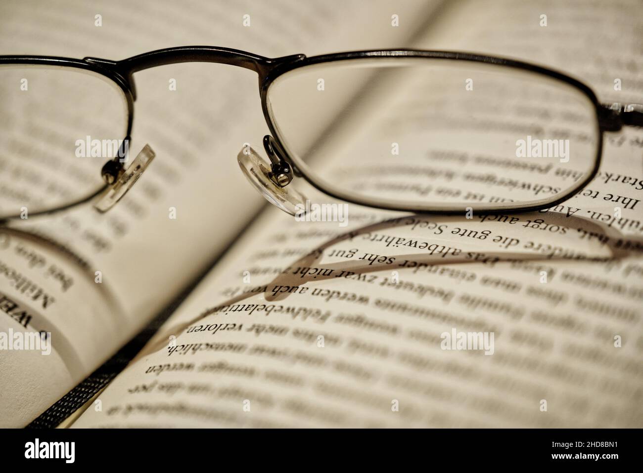 Close up of reading glasses lying on open book, selective focus Stock Photo