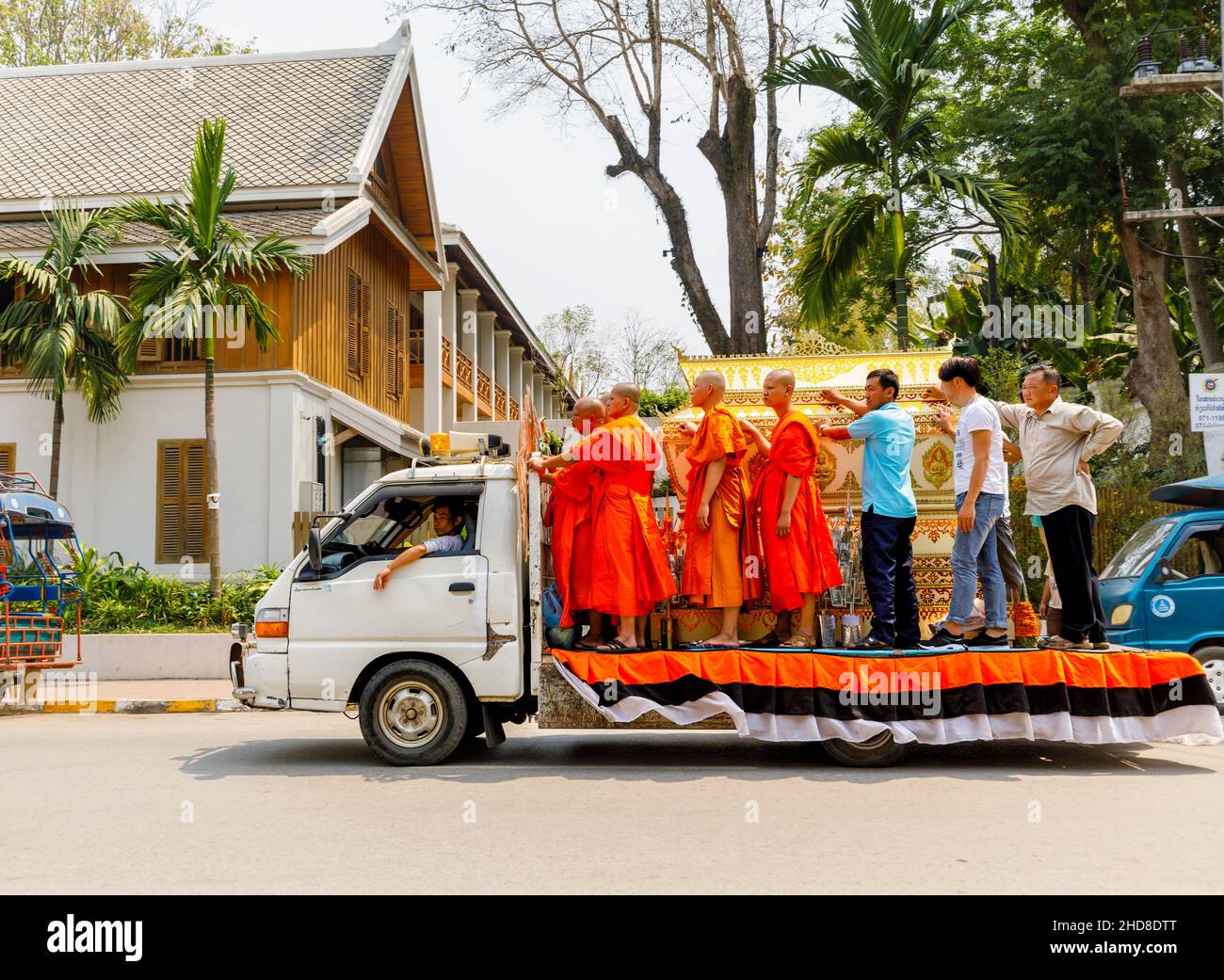 Street scene in Luang Prabang, northern Laos, south-east Asia: traditional saffron robed Buddhist monks stand on the back of a van Stock Photo