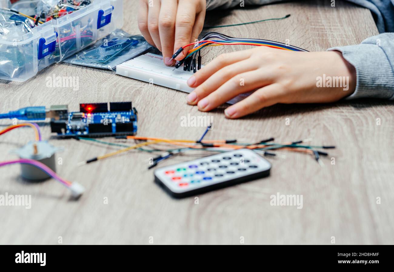 A child plugging cables to sensor chips while learning arduino coding ...