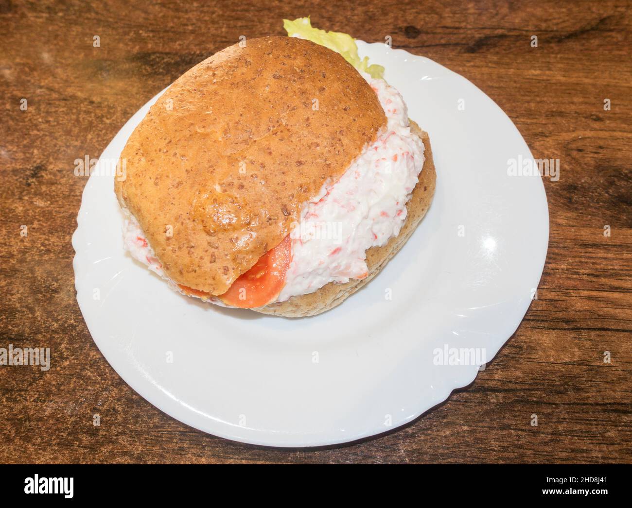 A crab paste sandwich in a brown or granary bread bun on a white plate Stock Photo