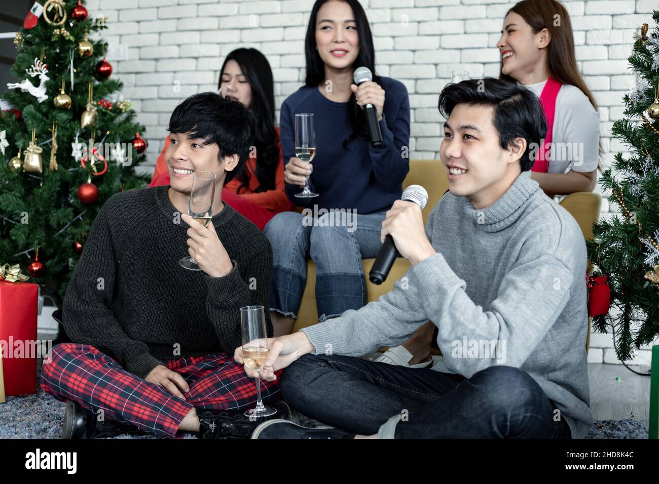 Happy party of young Asian with drink wine and sing a song at home in celebrate Christmas festival. Celebration of new year at house. Merry Christmas Stock Photo