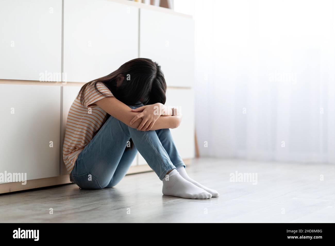 Upset long-haired brunette girl sitting on floor and crying Stock Photo ...