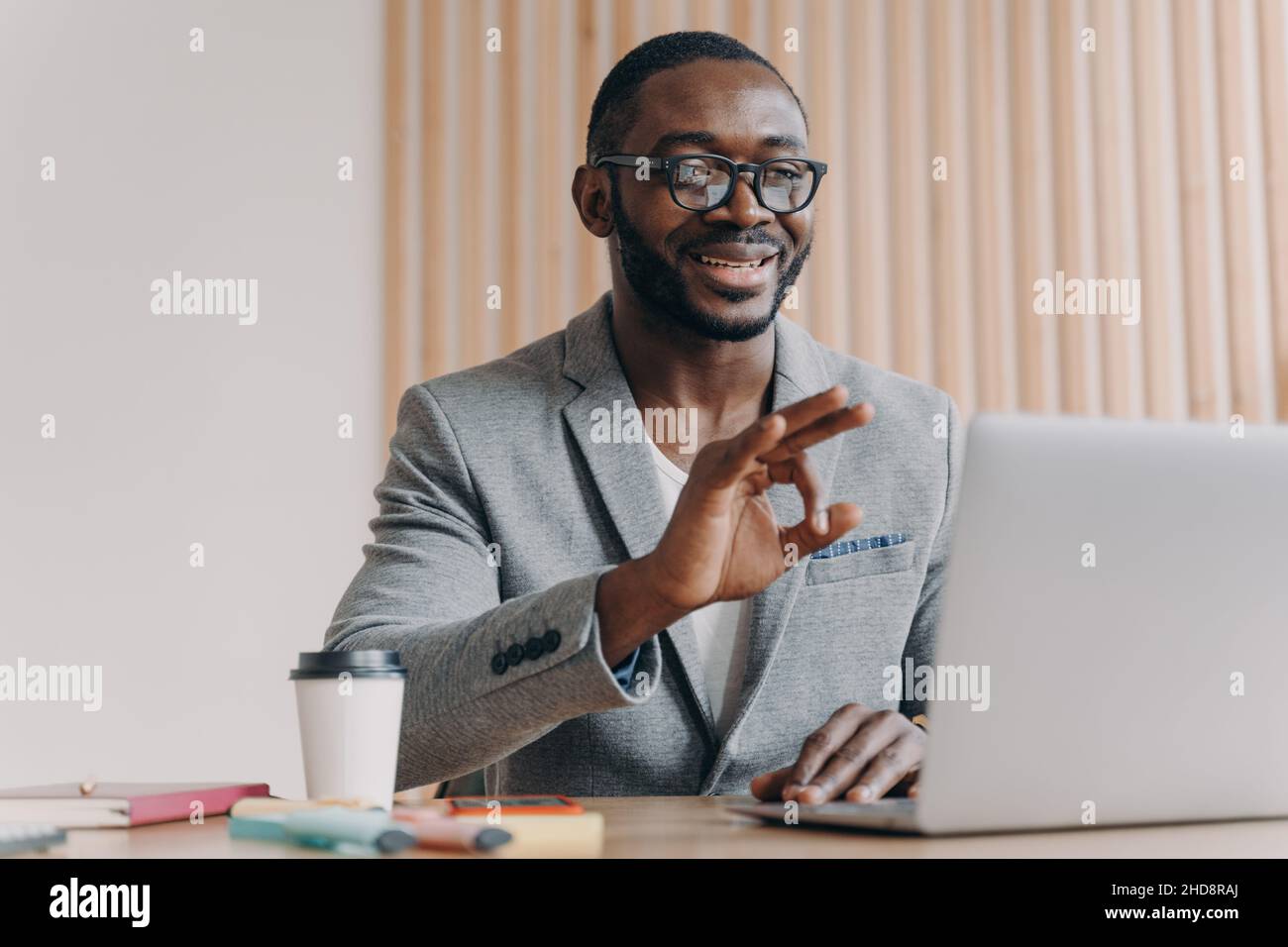 Young positive sitisfied african american businessman in suit talking with business partner online Stock Photo