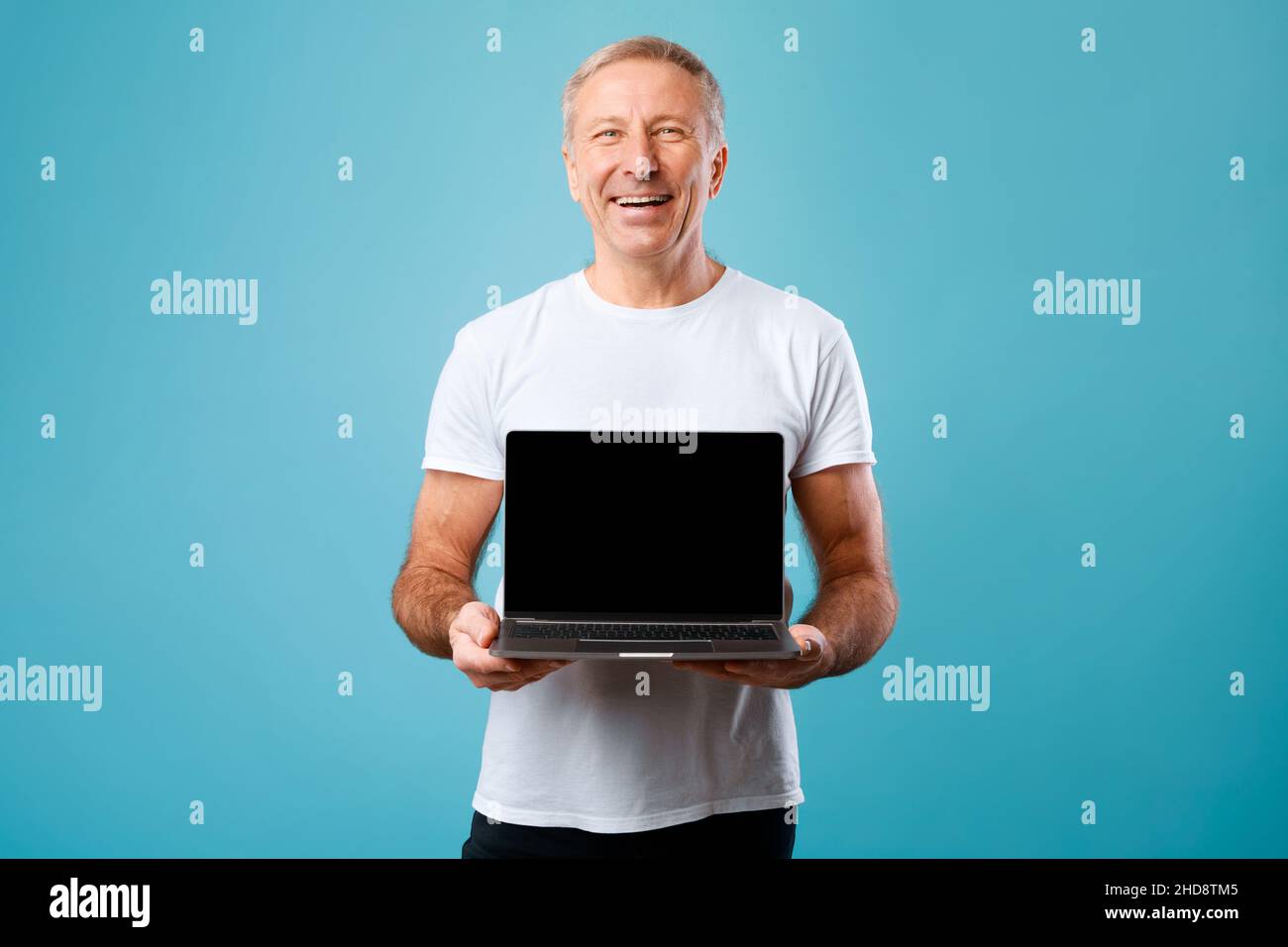 Happy mature man showing black empty pc screen Stock Photo
