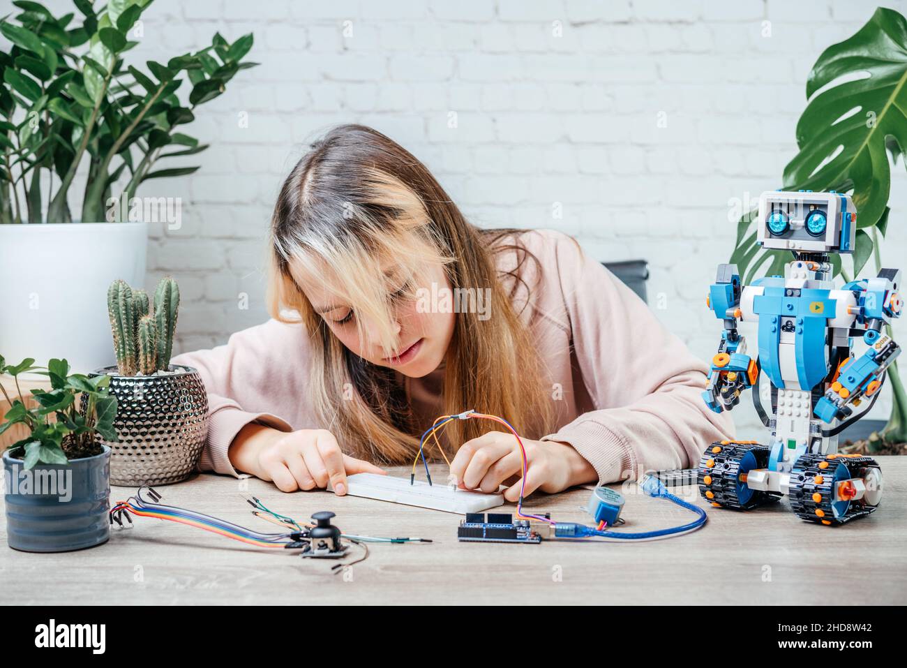 A teenager girl plugging cables to sensor chips while learning arduino ...
