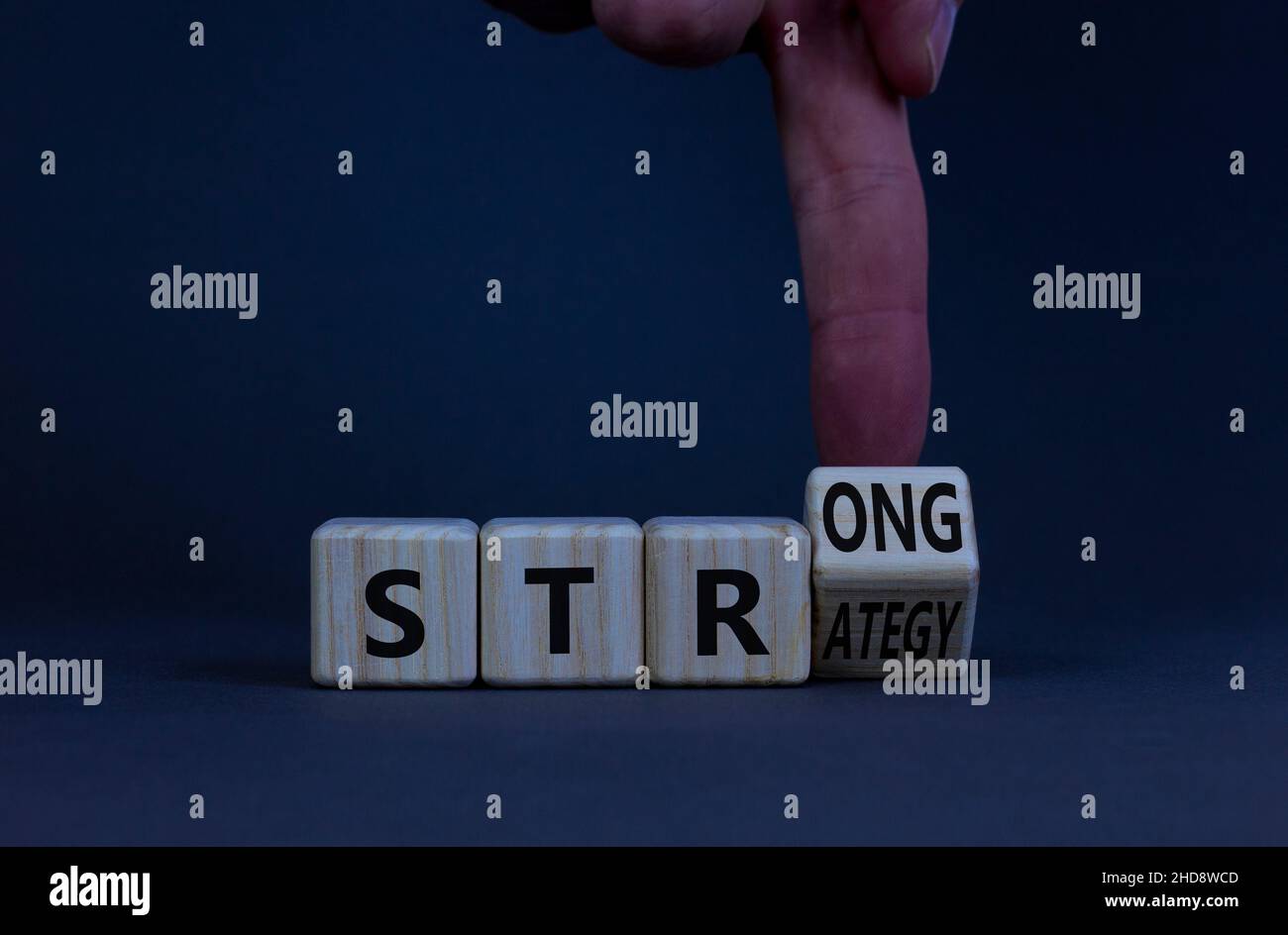 Strong strategy symbol. Businessman turns a wooden cube with words strong strategy. Beautiful grey table, grey background, copy space. Business and st Stock Photo