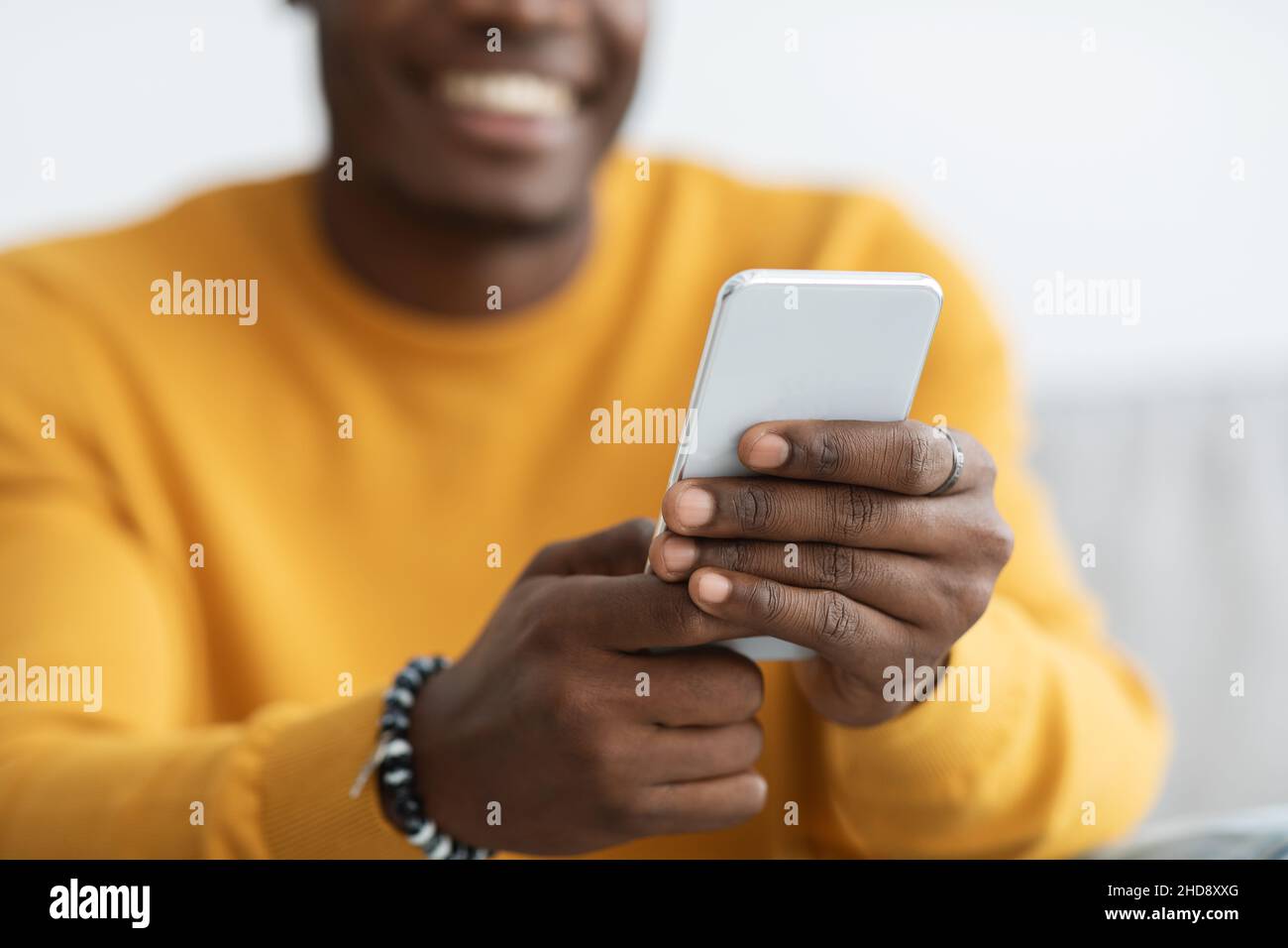 Unrecognizable black guy using mobile phone at home Stock Photo