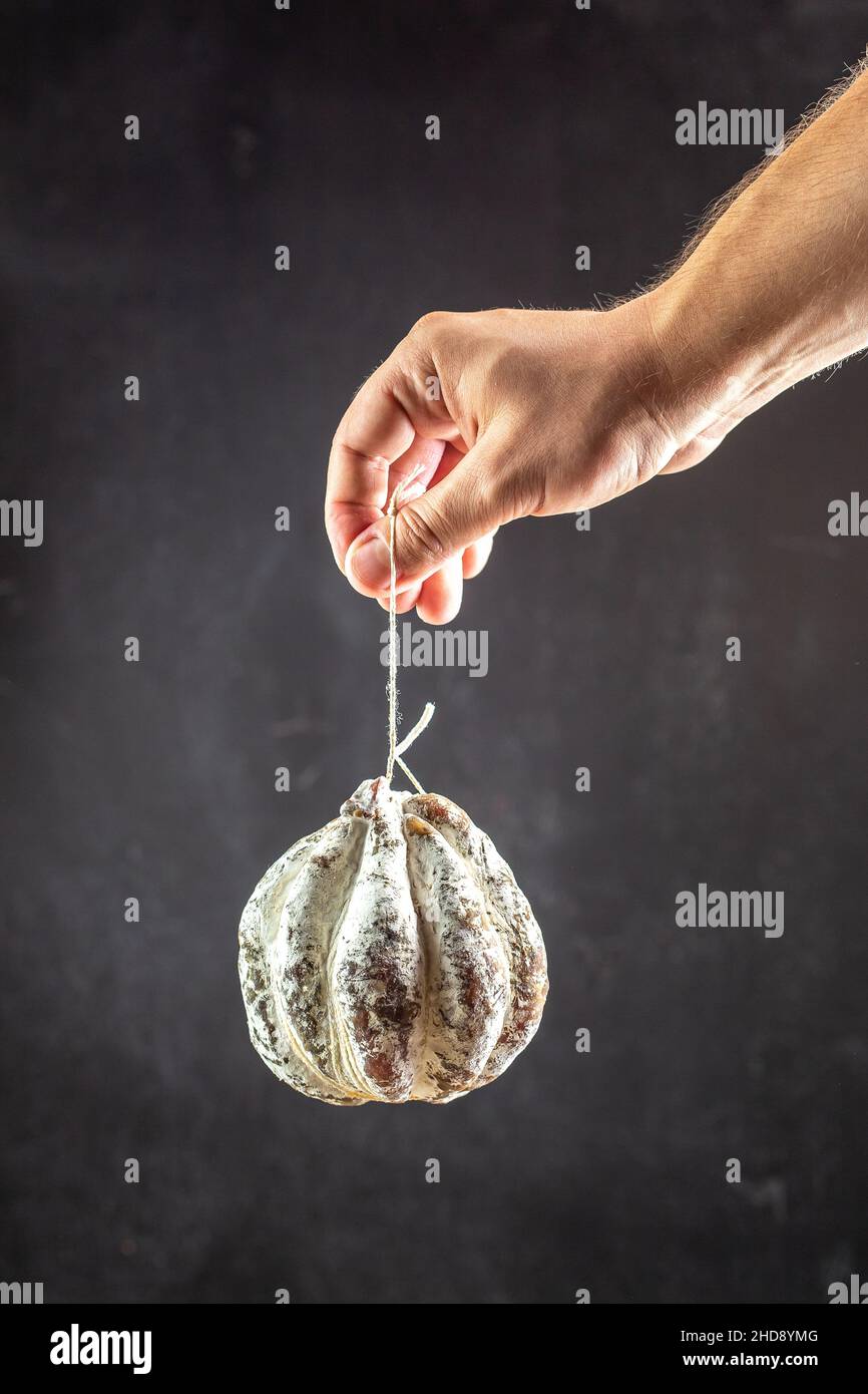 Man's hand holding a Matsik. Jerky pork meat placed in the pork stomach and dried for several months. Traditional Ukrainian appetizer. Stock Photo